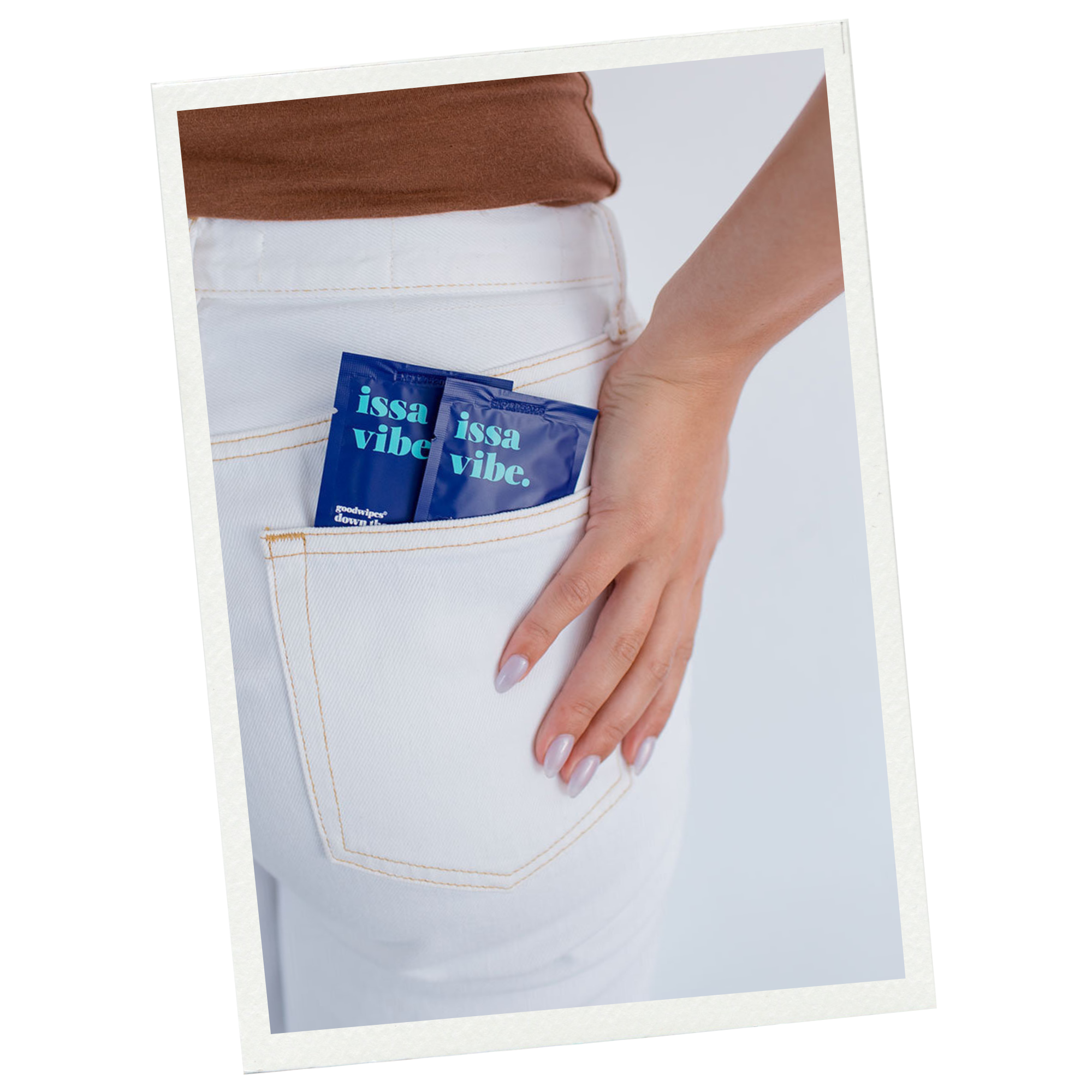 Close-up of a person wearing white jeans with their hand in the back pocket, holding two blue sachets labeled 'issa vibe.'