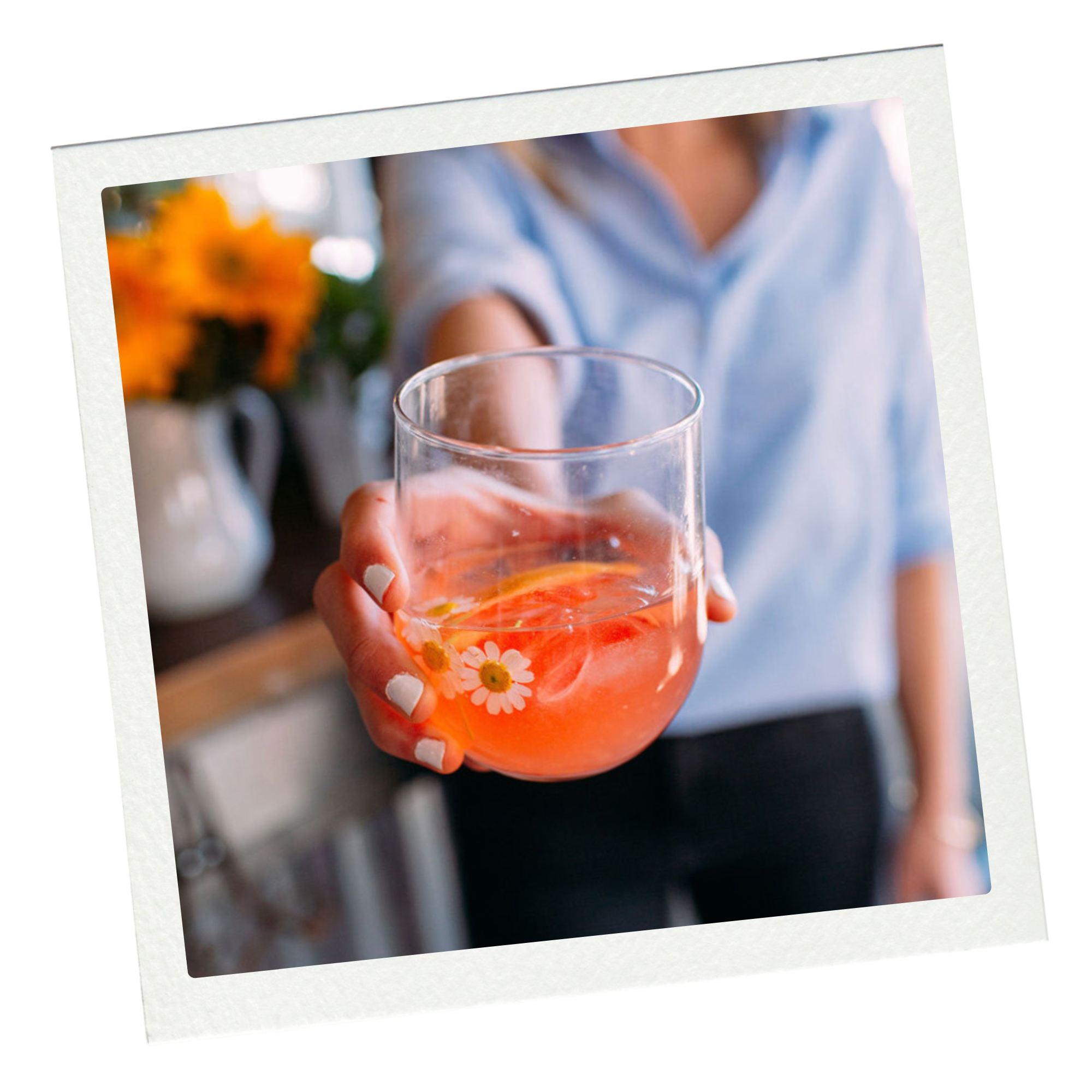 Person holding a glass with pink-colored drink and flower design, possibly in a kitchen or dining area.
