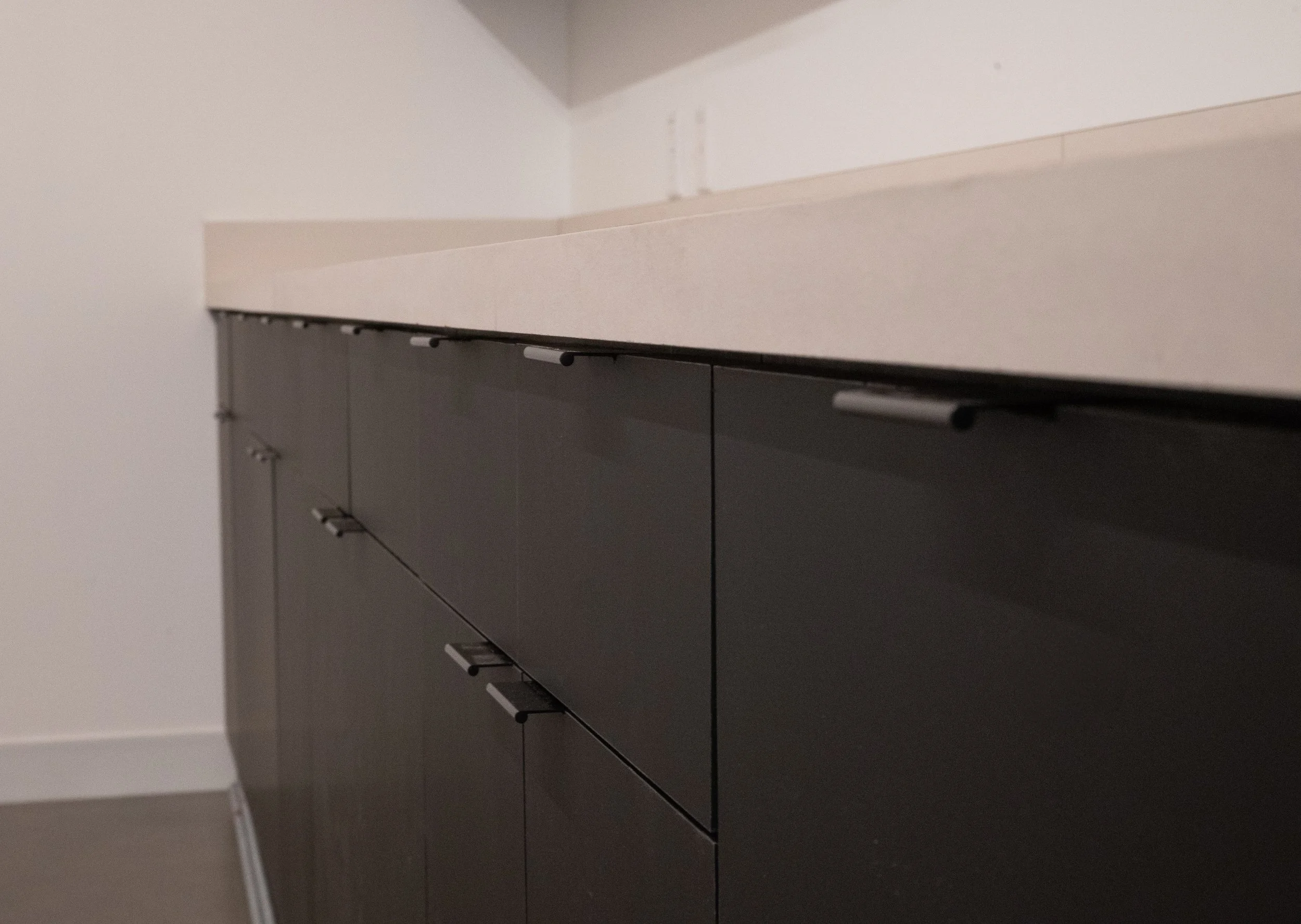 Close-up of a black cabinet with multiple drawers against a plain white wall.