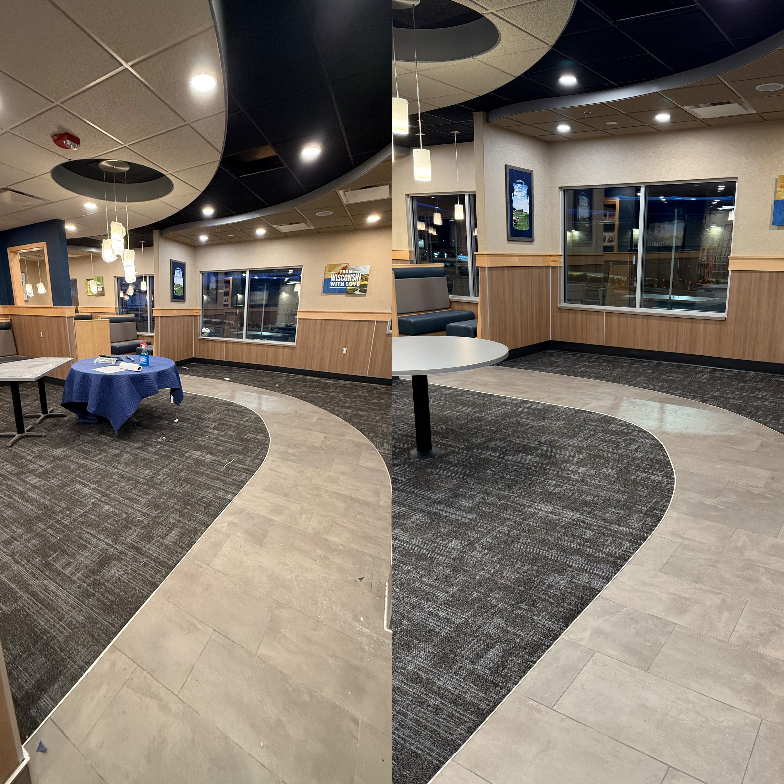 Interior of a restaurant or cafe with a curved pathway on the floor, wood-paneled walls, hanging pendant lights, large windows, and framed wall art.