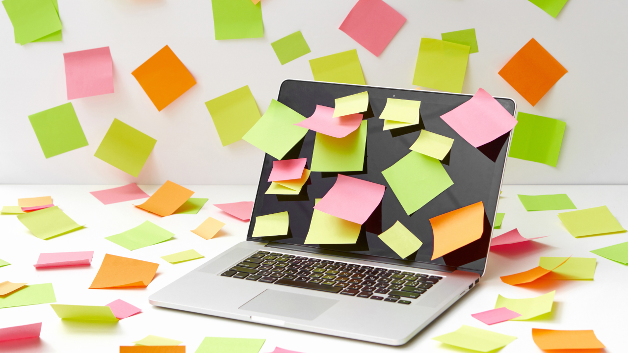 A laptop covered in post-it notes with overdue tasks