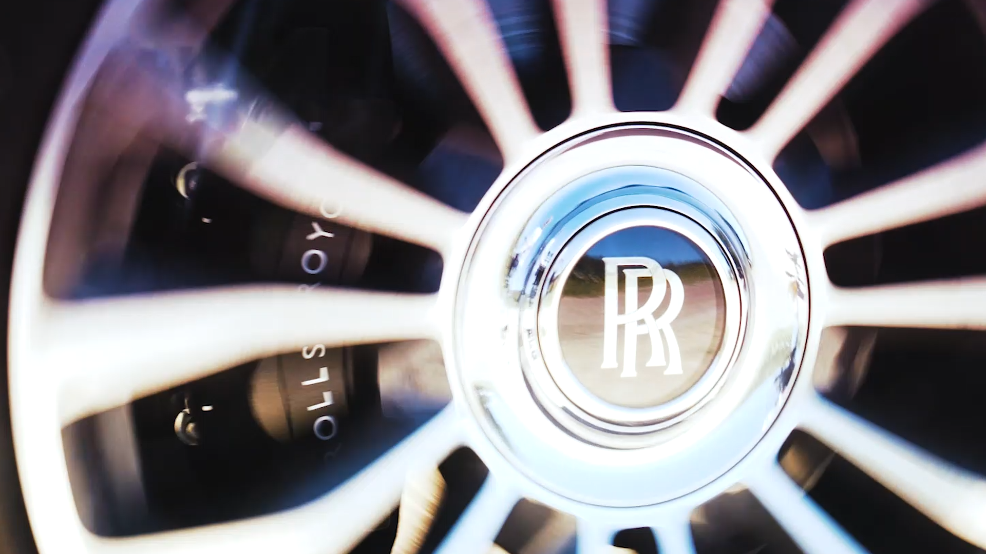 Close-up of a Rolls-Royce wheel with the engraved logo in the center and visible brake calipers.