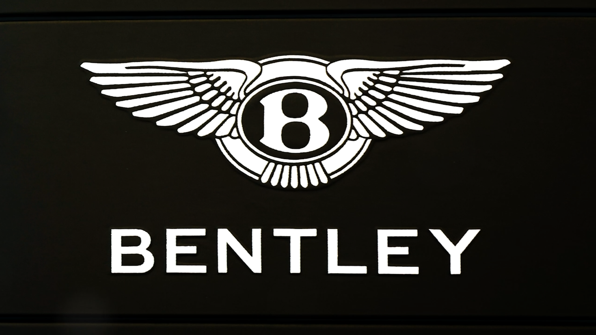 Bentley logo featuring a stylized letter 'B' with wing-like designs and the word 'BENTLEY' below.