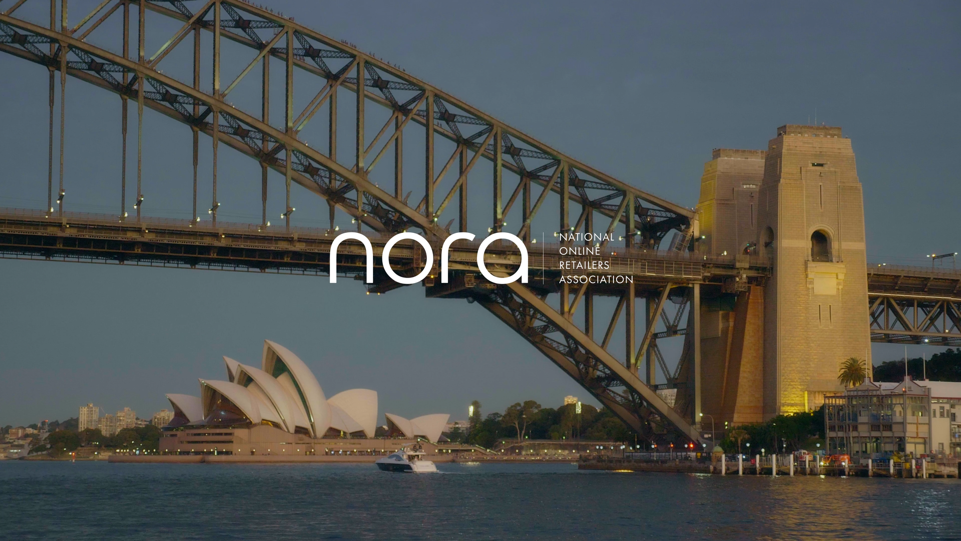Sydney Harbour Bridge and Sydney Opera House at dusk with a small boat on the water in front.