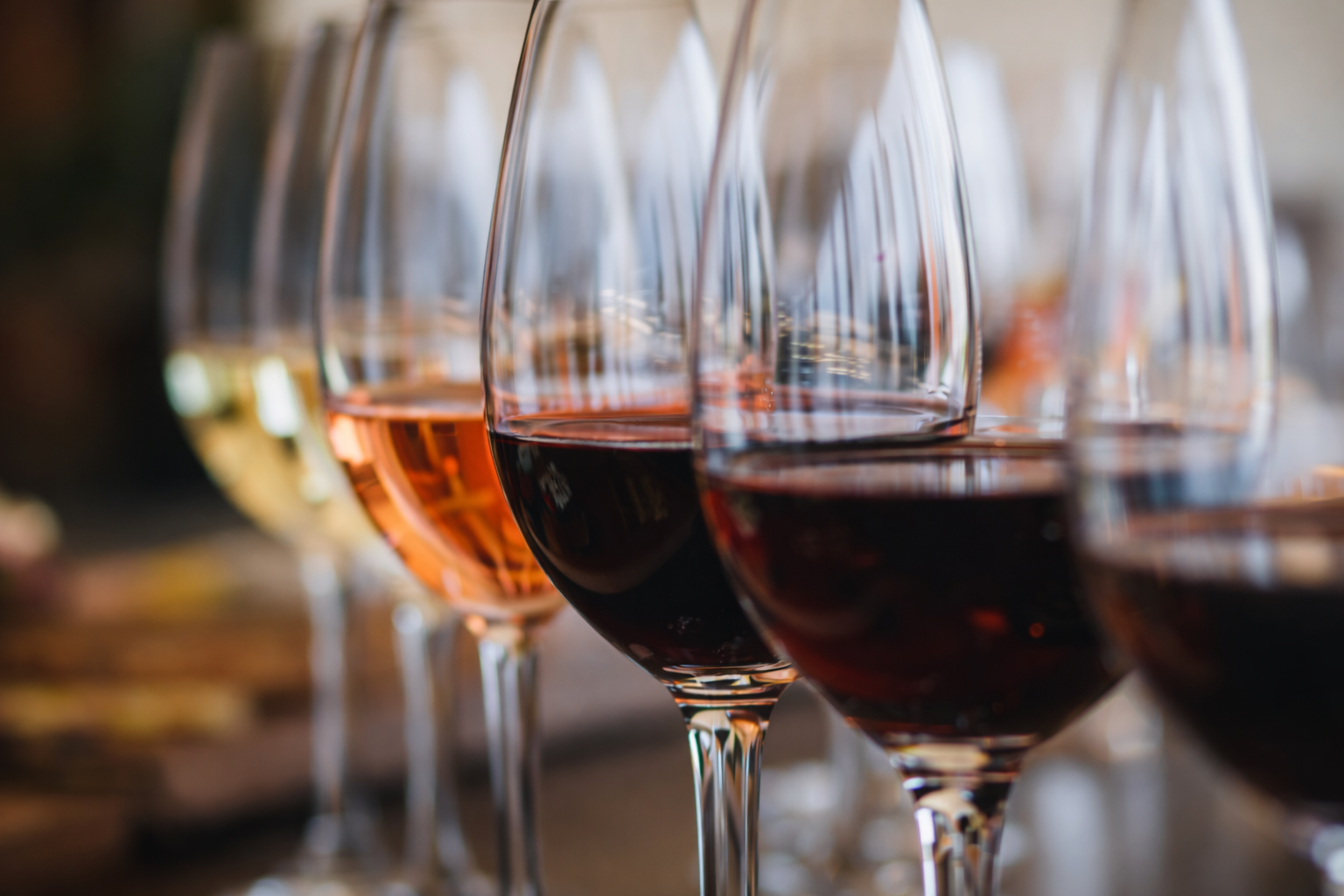 Multiple glasses of red and white wine on a table.