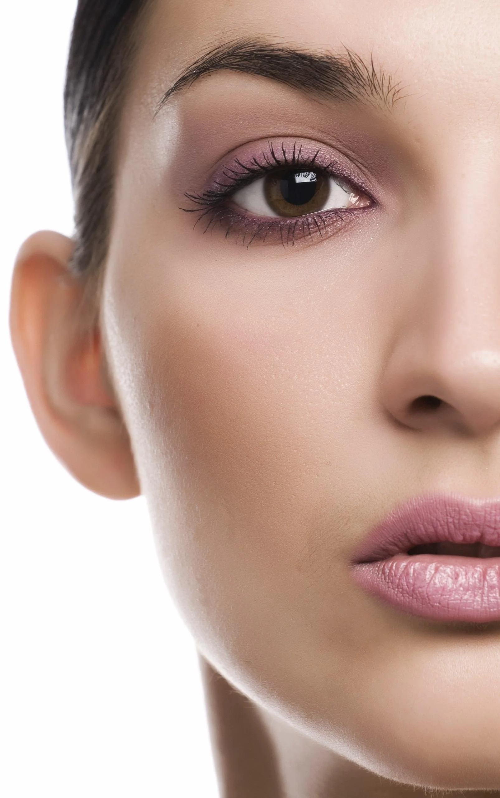 Close-up of a woman's face showing her eye, cheek, and lips with makeup and smooth skin.