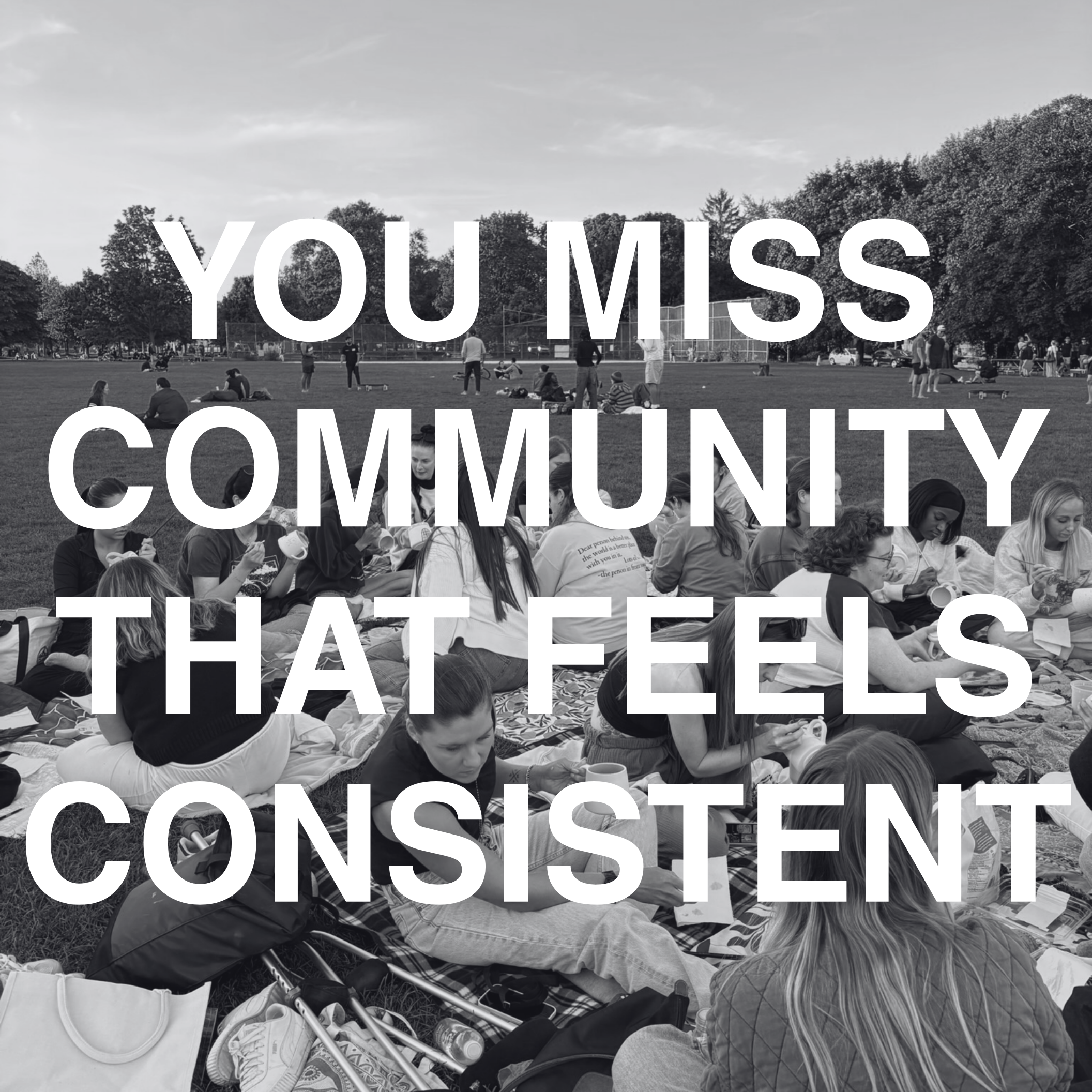 A black-and-white photo of a large group of people sitting on a grassy field with trees and a sports field in the background. Overlaid text reads: "You miss community that feels consistent."