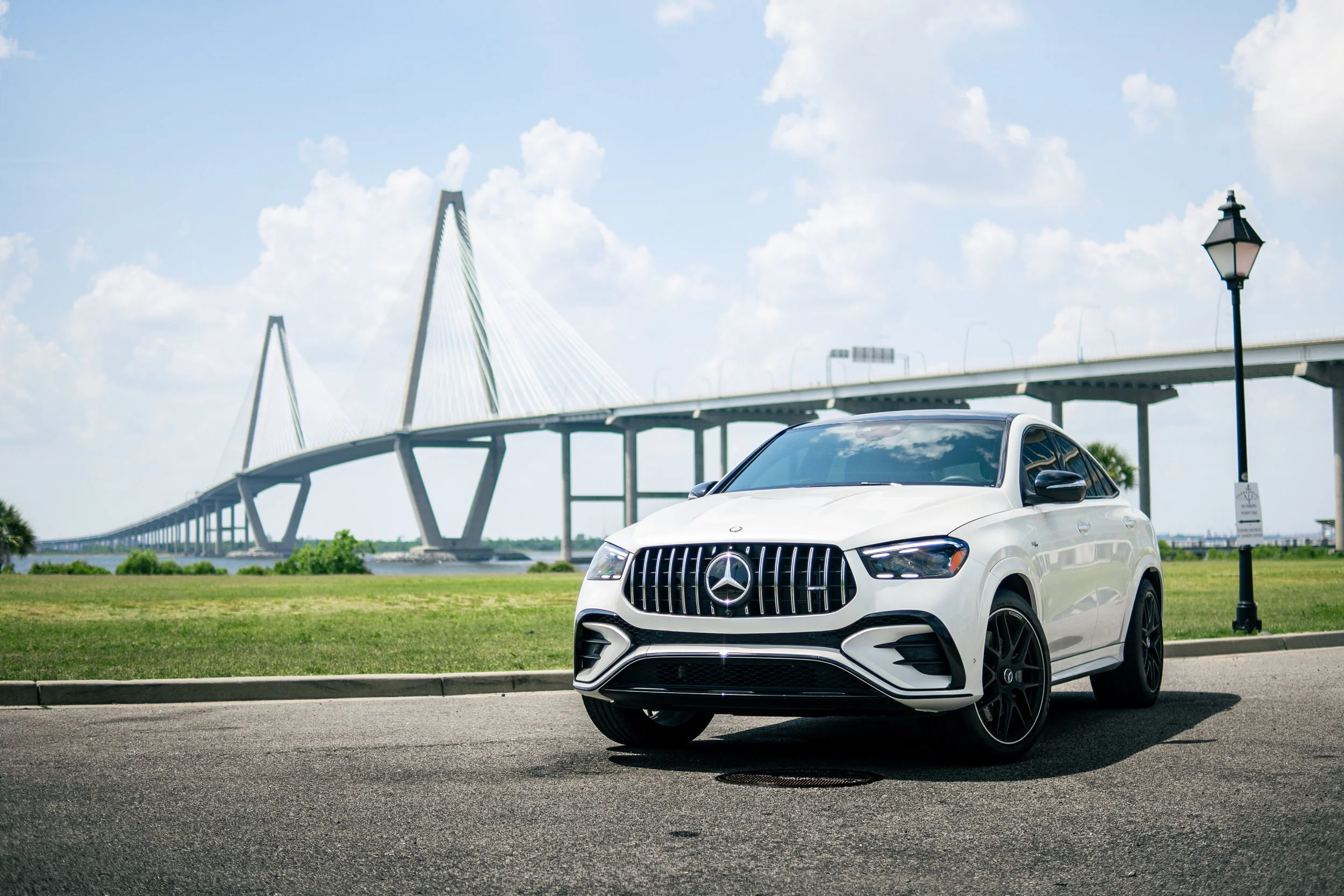 A white Mercedes-Benz SUV parked on a city street with a bridge in the background.