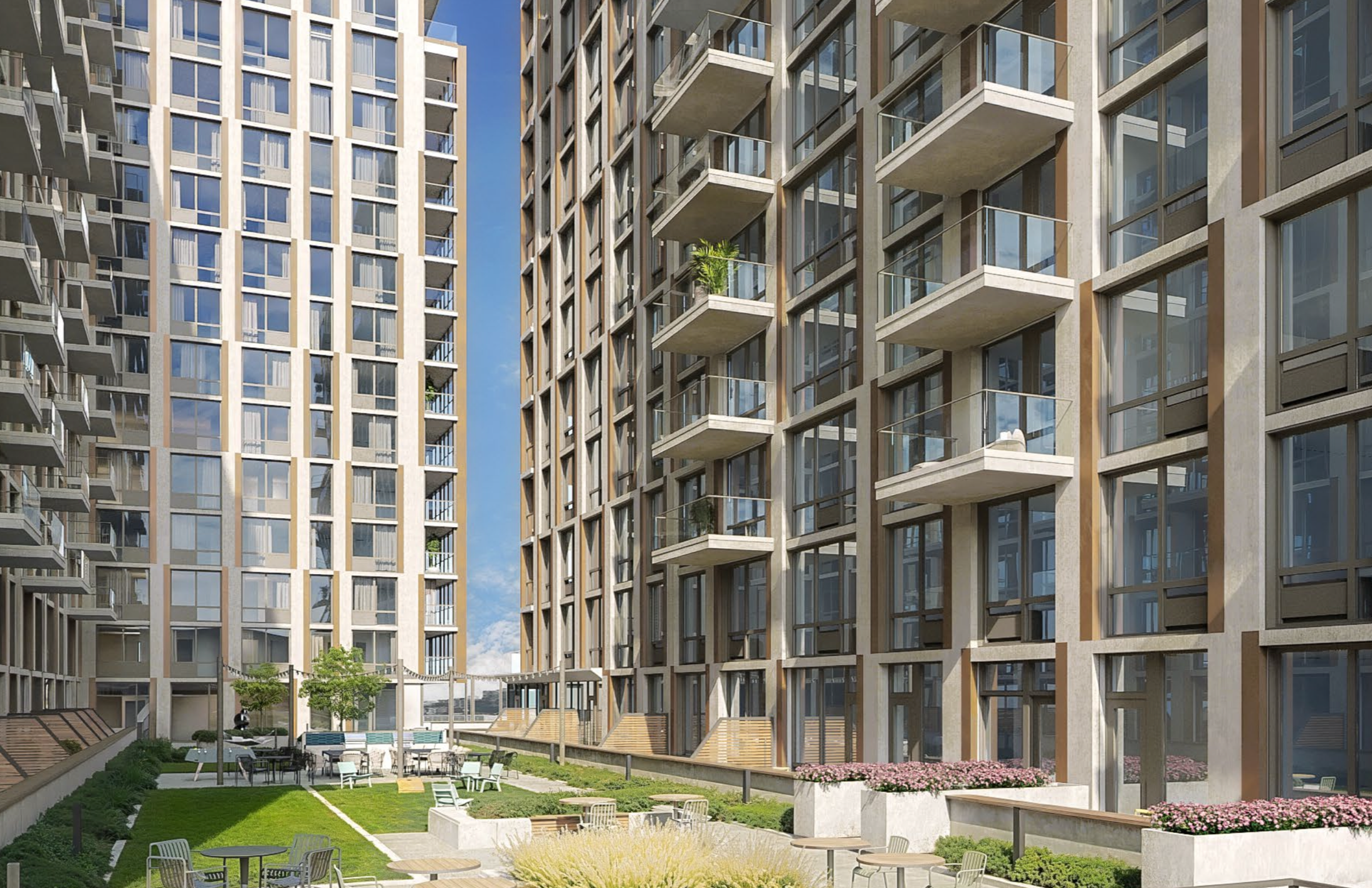 Modern apartment buildings with glass balconies surrounding a landscaped courtyard featuring benches, tables, and a small garden area.