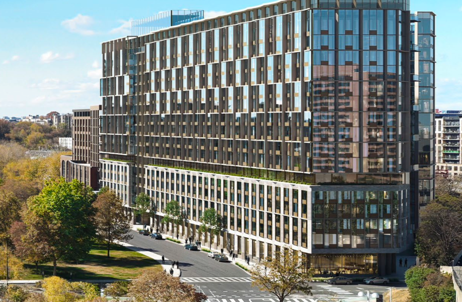 Modern multi-story office building with glass facade and distinctive vertical window design, surrounded by trees and cityscape under clear blue sky.