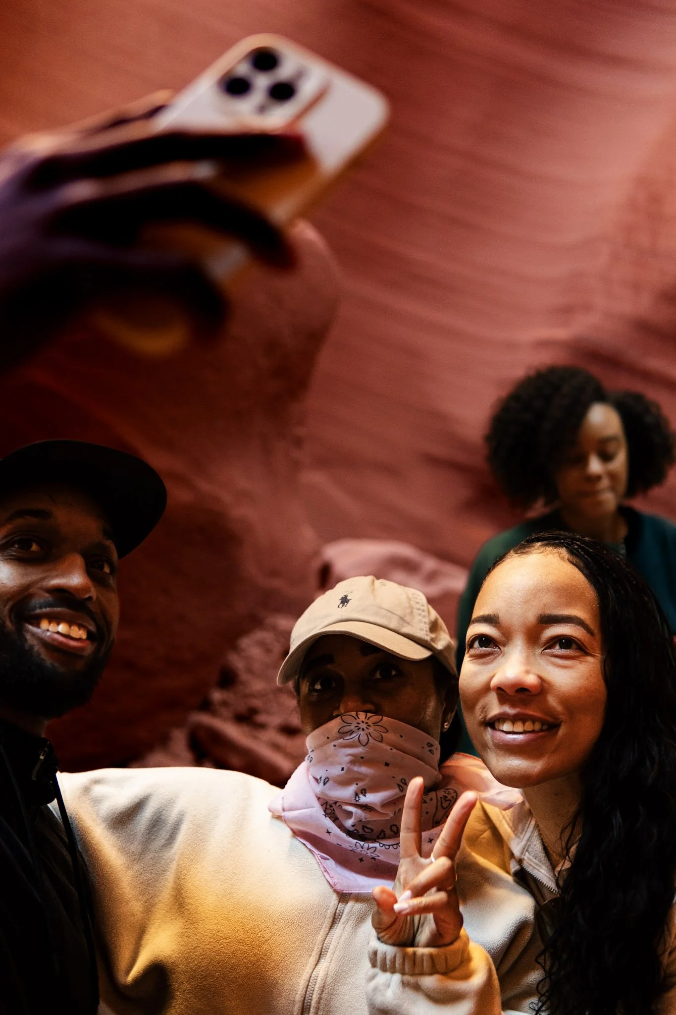 Group of four diverse friends taking a selfie, with red rock formations in the background.