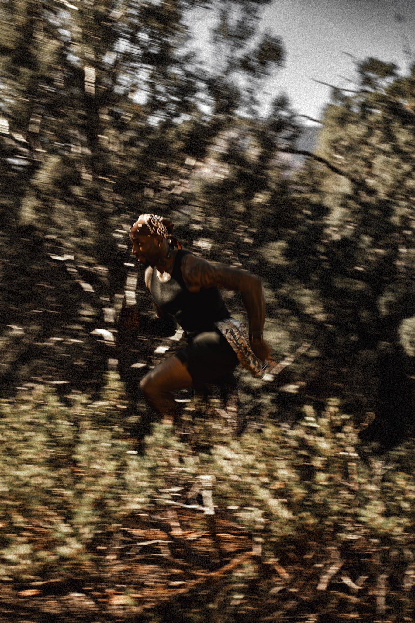 A man running through a forested area with blurred trees and bushes in the background.