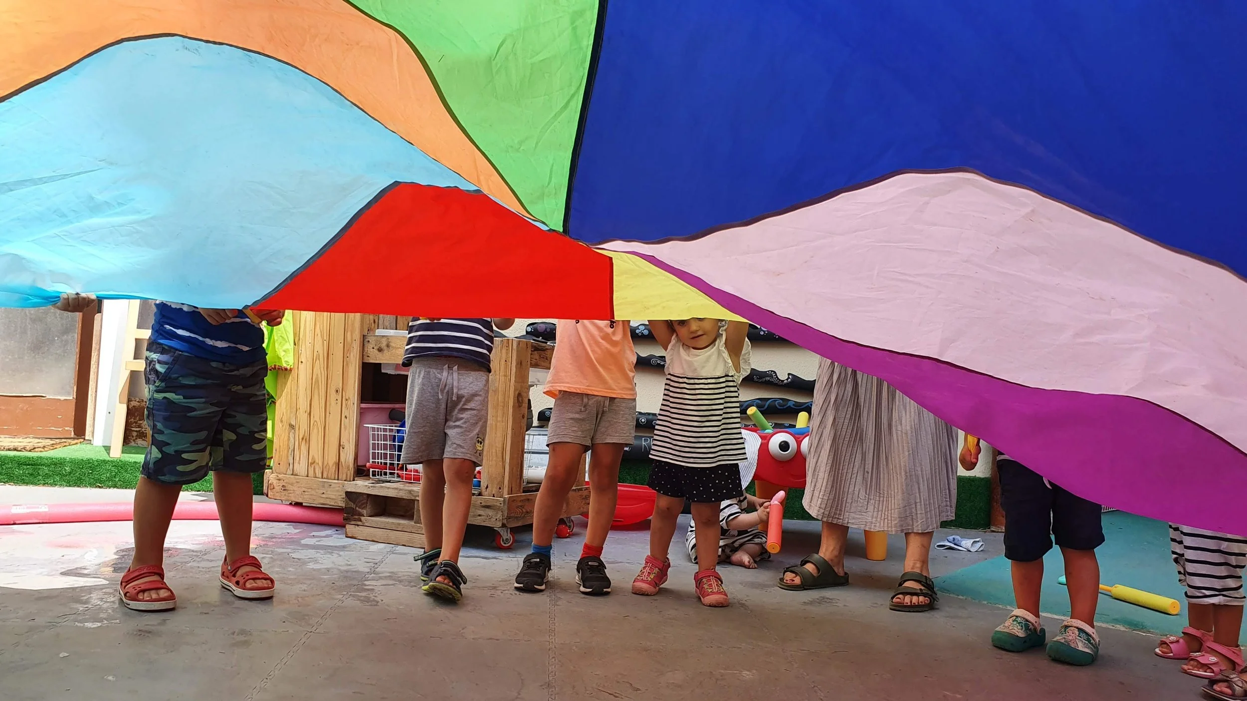 Kids flapping a multi-color parachute together