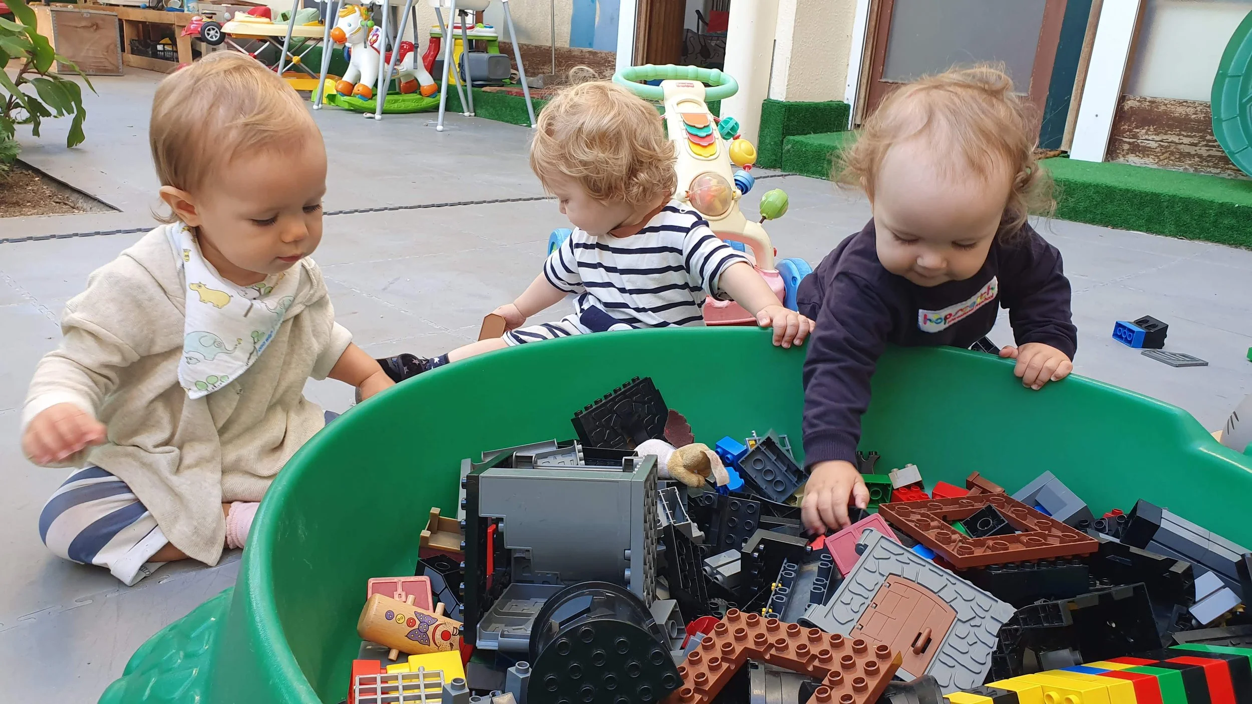 Toddlers sorting through a bin of building blocks