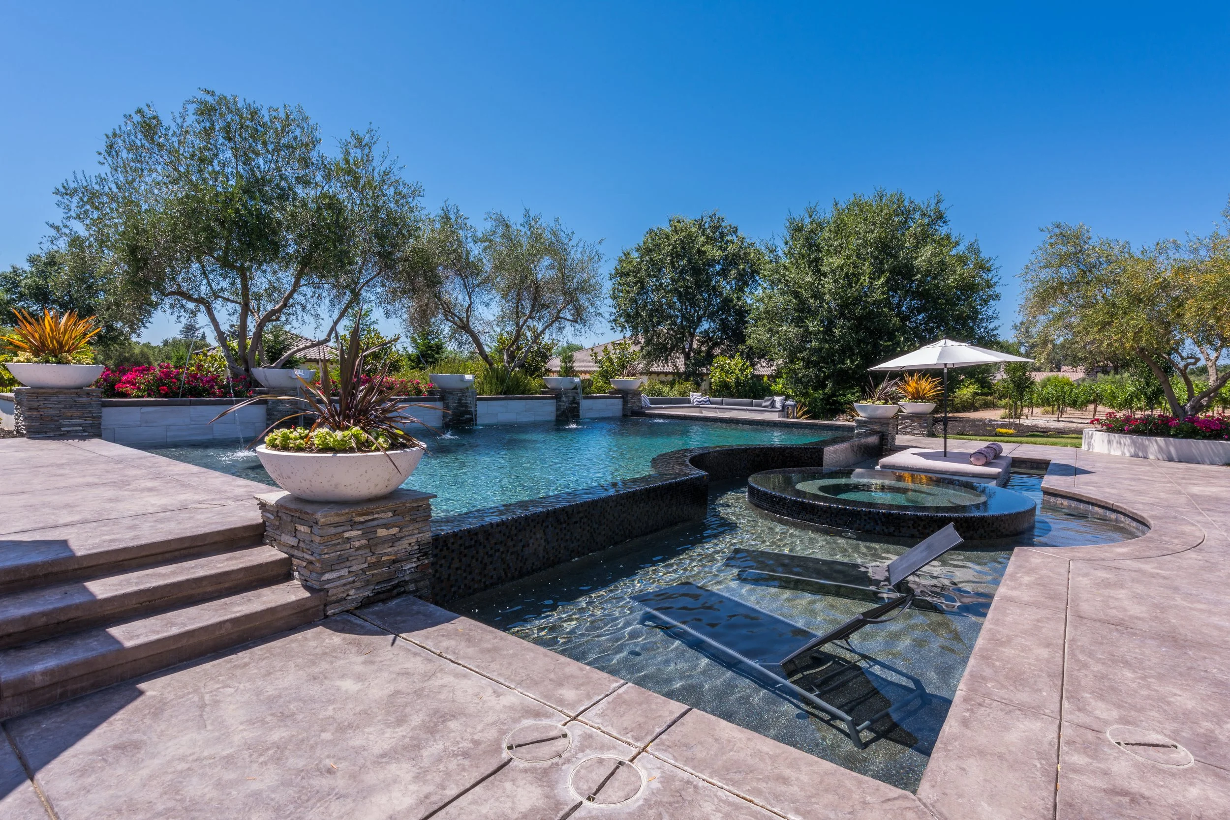 Infinity edge pool with perimeter overflow spa, firepit and water feature wall