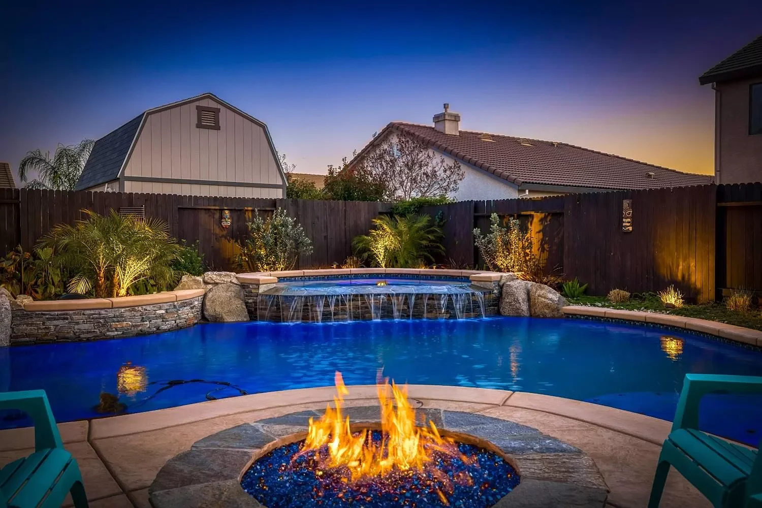 Freeform pool with raised infinity edge spa, tropical vibes and stone fire pit