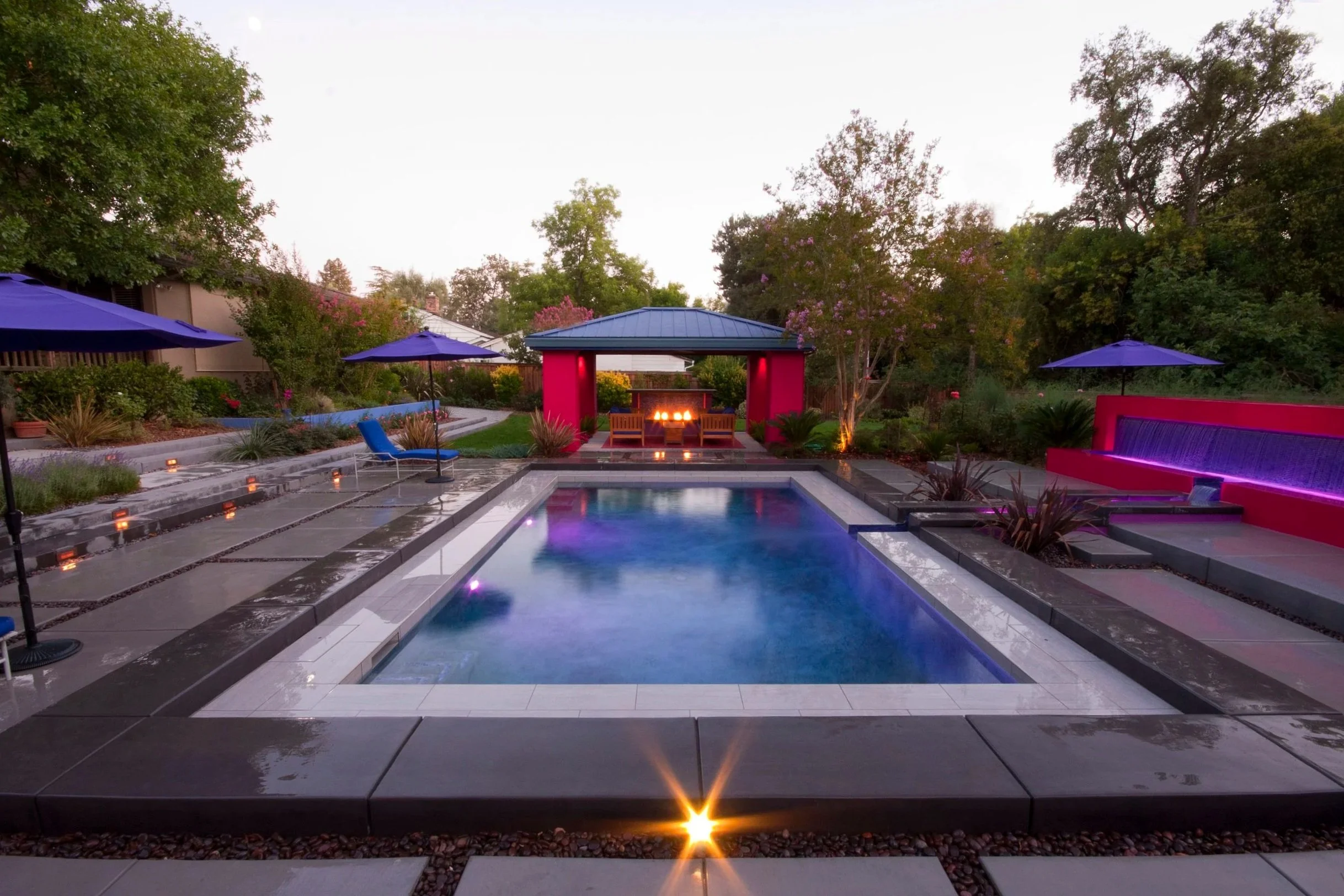 Modern pool with rised perimeter, concrete step pads, fountain wall and LED lights