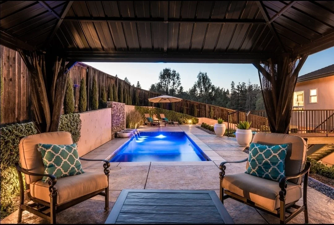 Modern pool with stone wall, water pots and LED colored lights and covered patio