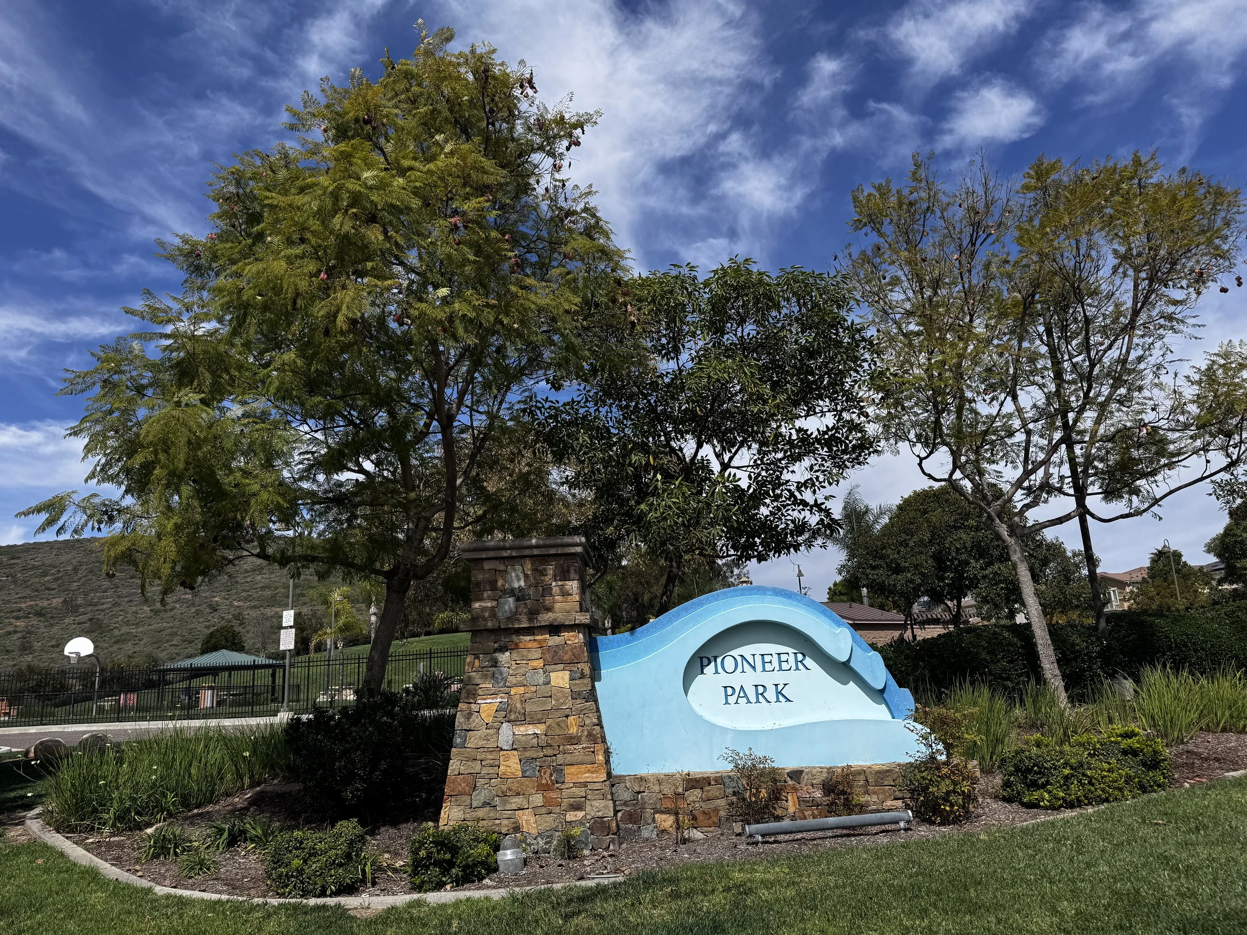Sign at Pioneer Park with trees and blue sky in the background.