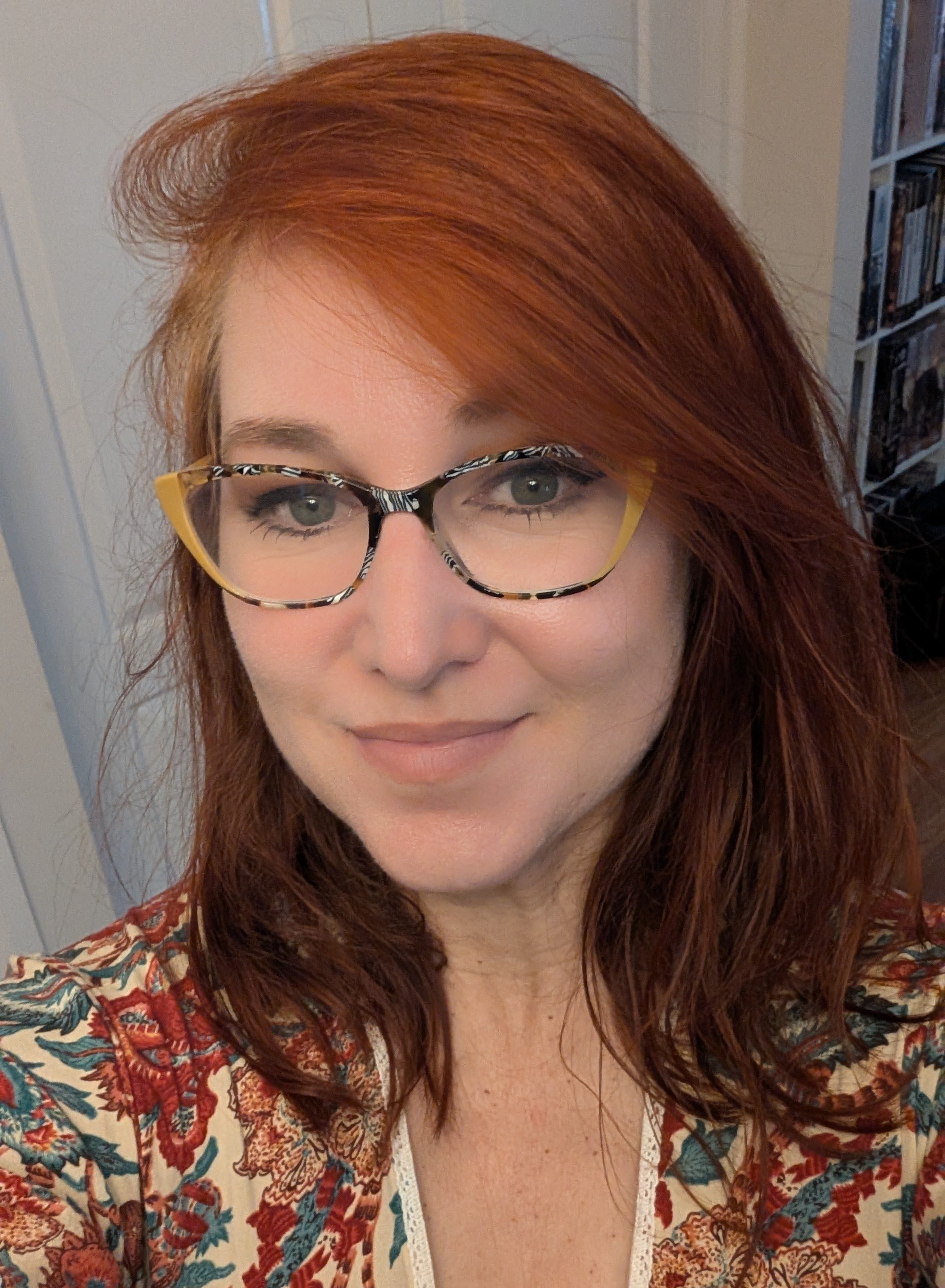 Portrait of Rise Finance bookkeeping team member, woman with red hair, wearing glasses, smiling.