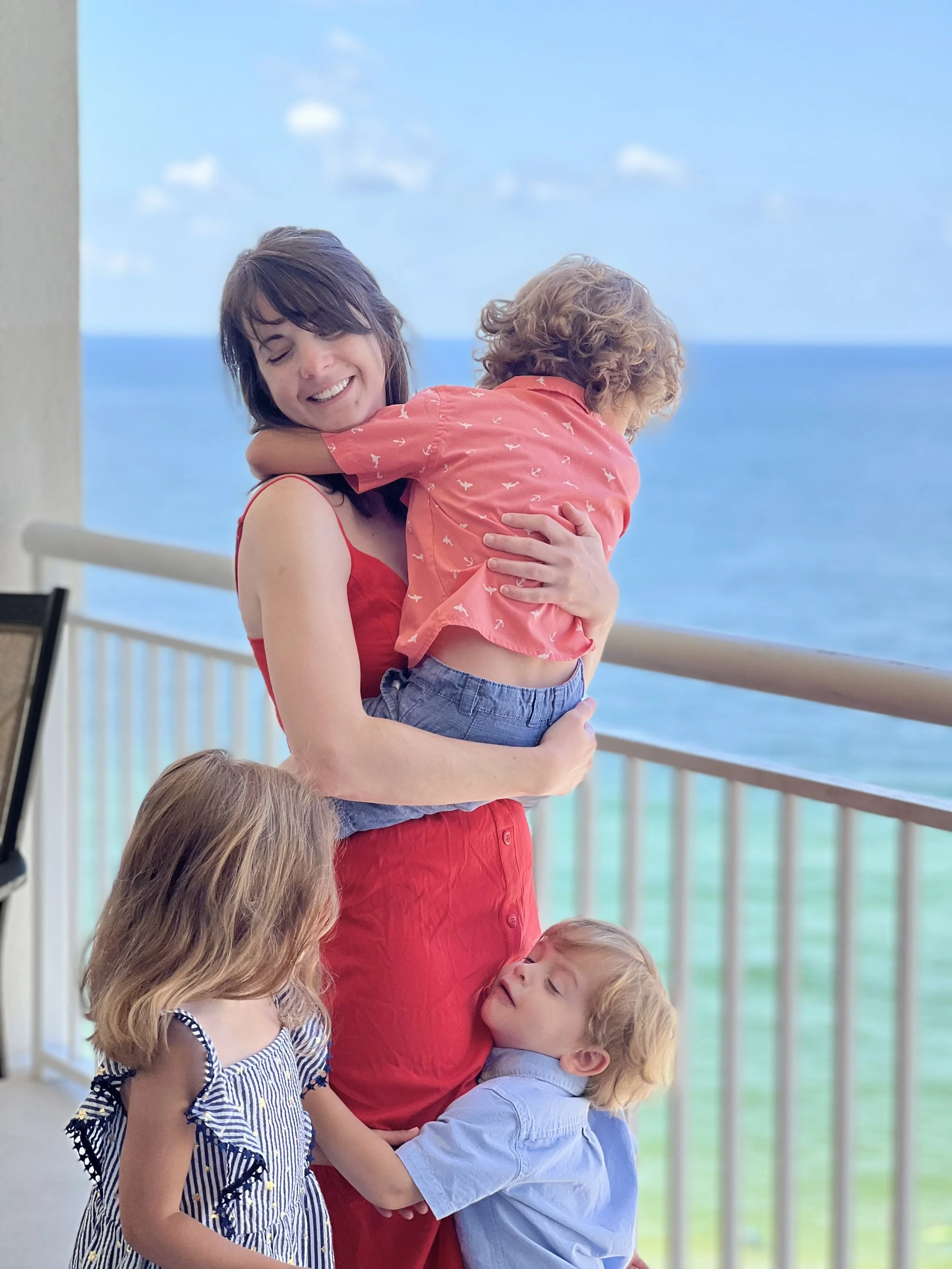 Dr. Moore laughing with her three kids, with an ocean view in the background.