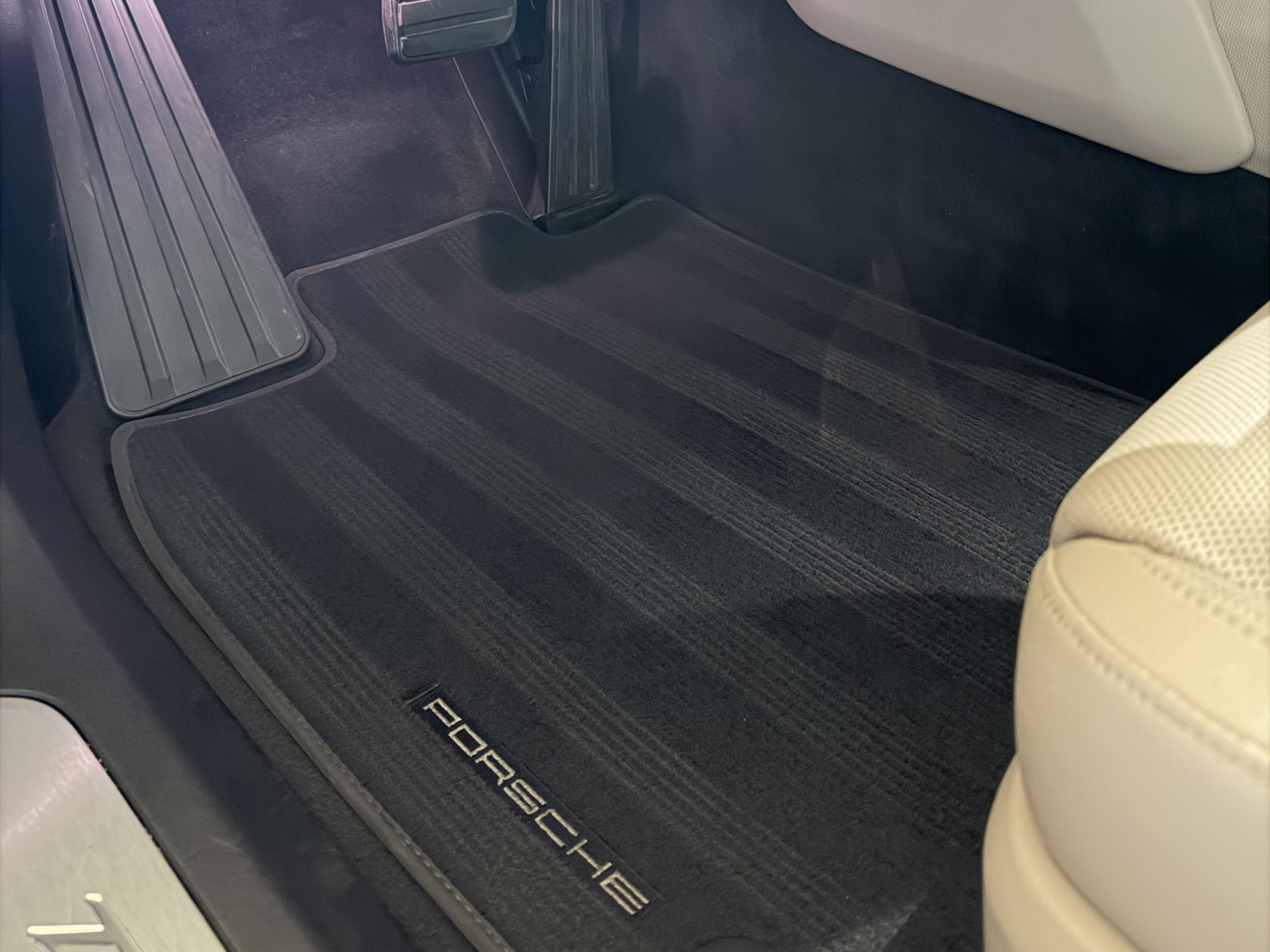 Close-up of a car interior showing the floor mat, accelerator pedal, and a small part of the beige seat.