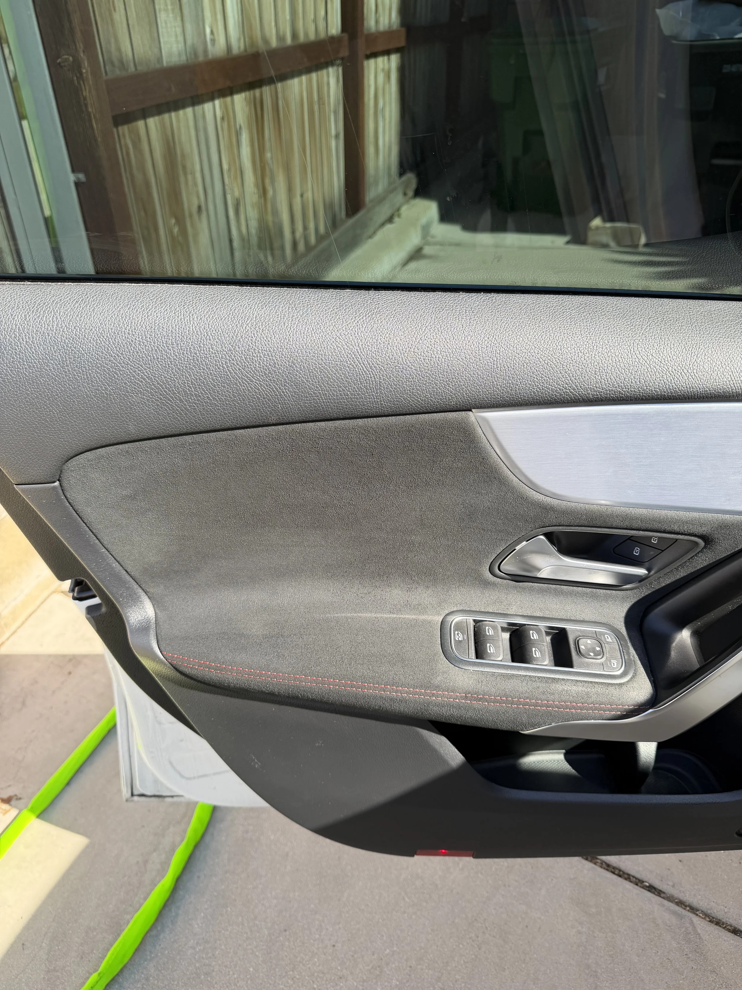 A close-up view of a car door interior, showing window controls, a door handle, and a textured panel.