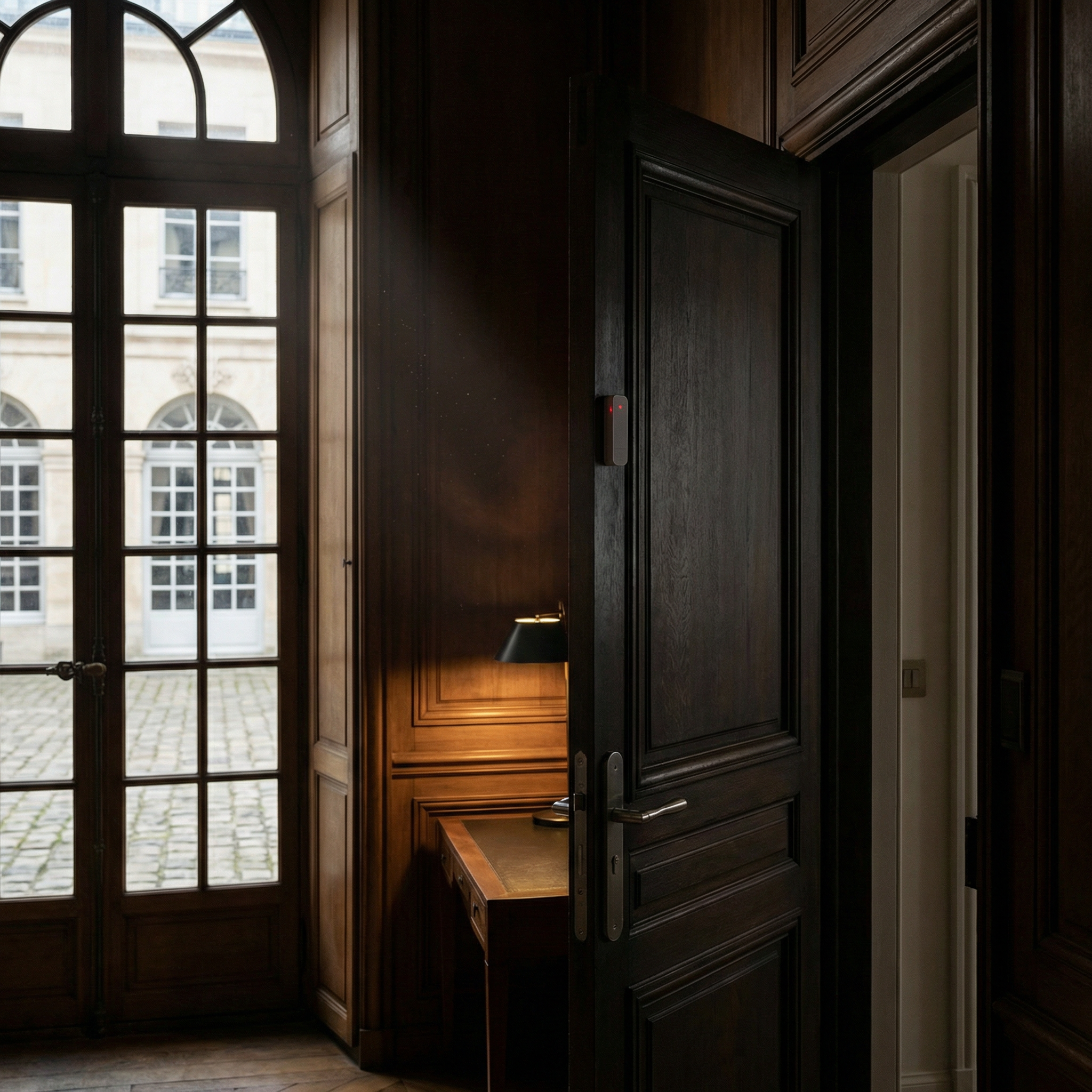 Une pièce avec une grande fenêtre en verre divisée en plusieurs petits carrés, un mur en bois foncé, et une porte en bois noir partiellement ouverte. La porte comporte un capteur d'ouverture de porte. Techniserv Normandie, systèmes d'alarme.