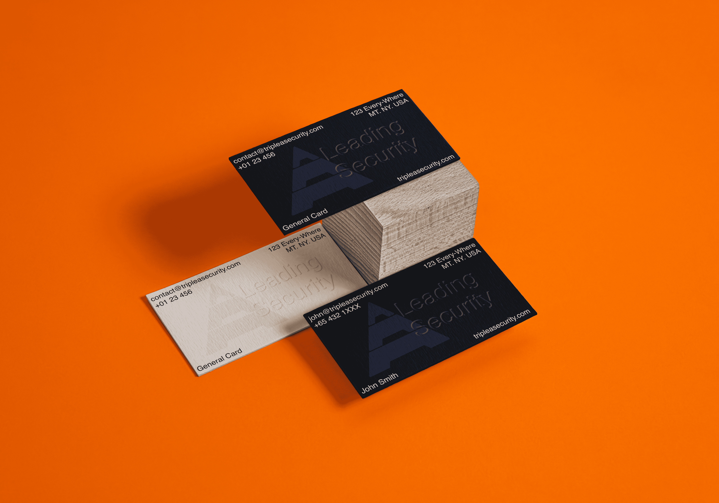 Two business cards, one black and one white, placed on a small wooden block on an orange background. The black card reads "Leading Security" with contact information, and the white card has similar details with a slightly different design.