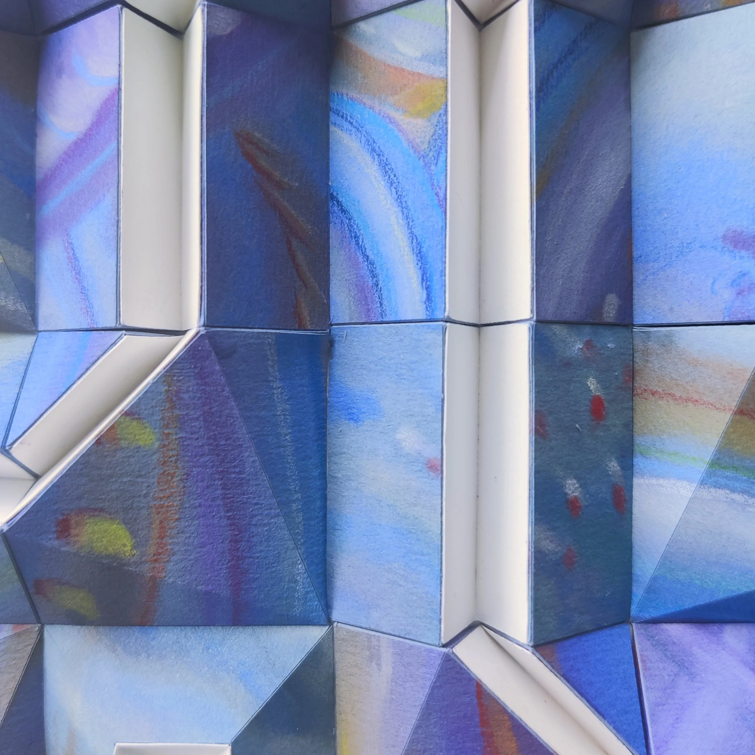 Colorful geometric paper sculpture with painted patterns and structured folds.