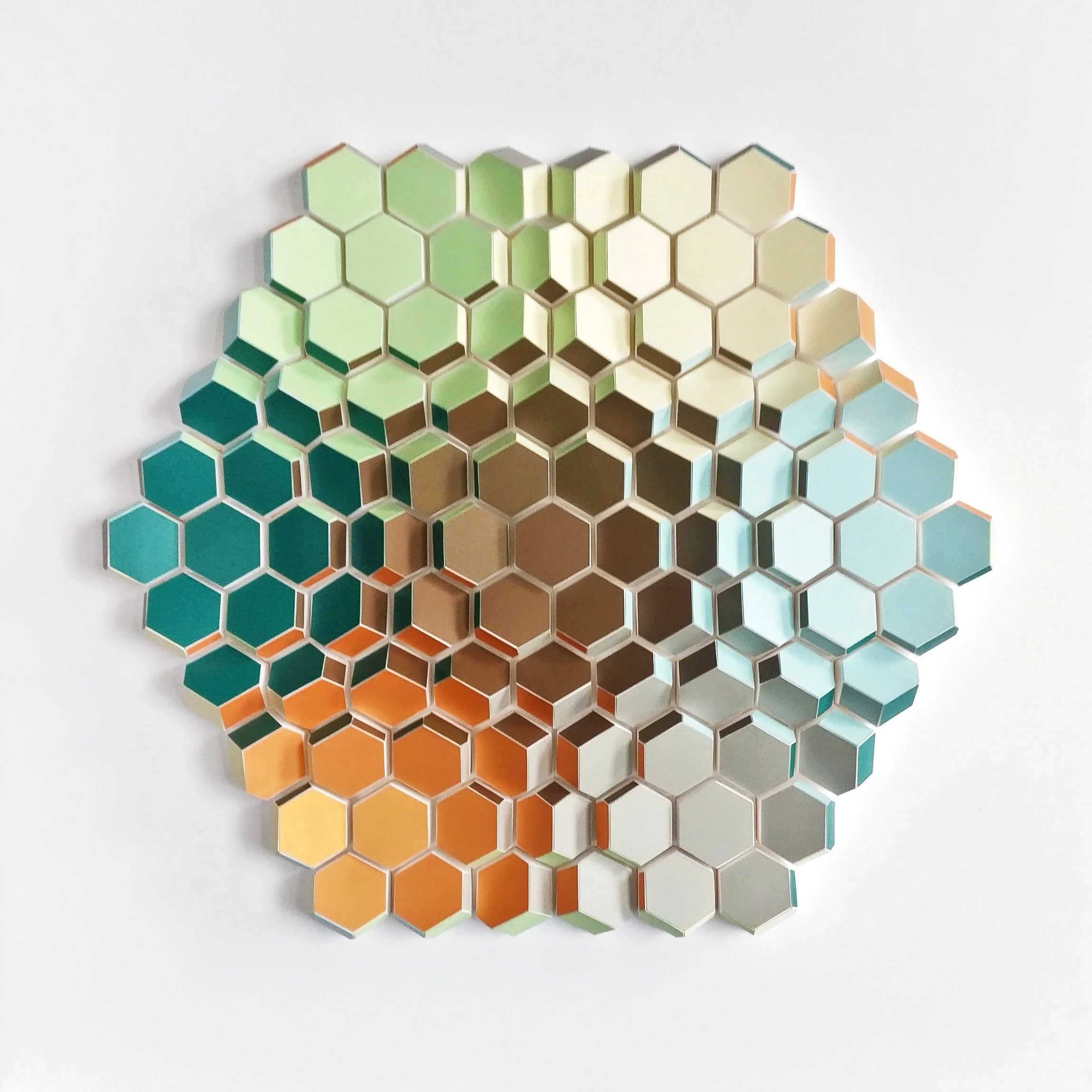 Decorative hexagonal mirror wall art with a gradient of colors from green at the top and transitioning through teal and orange toward the bottom, mounted on a white background.