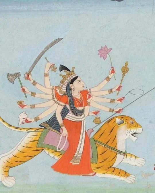 Hindoeïstische godin met meerdere armen, zittend op een tijger, houdende een lotusbloem en andere symbolen.