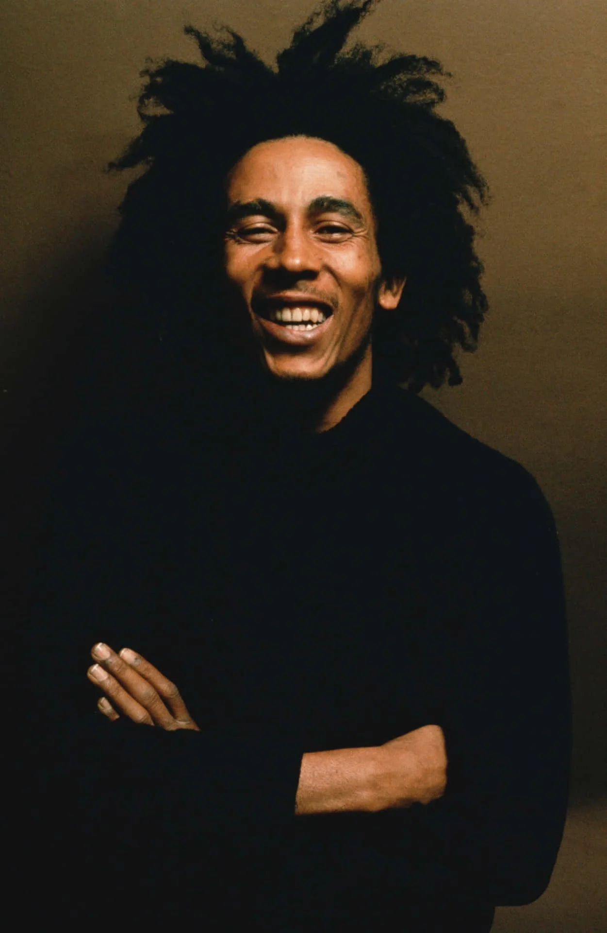 Portrait of Bob Marley smiling with his dreadlocks down, looking relaxed and expressive.