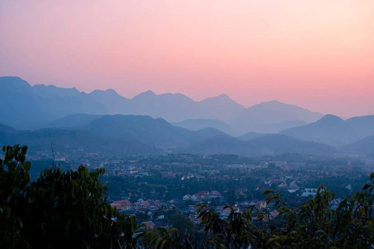 Landscape of a town in a valley with mountain ranges in the background during sunset with a pink sky.