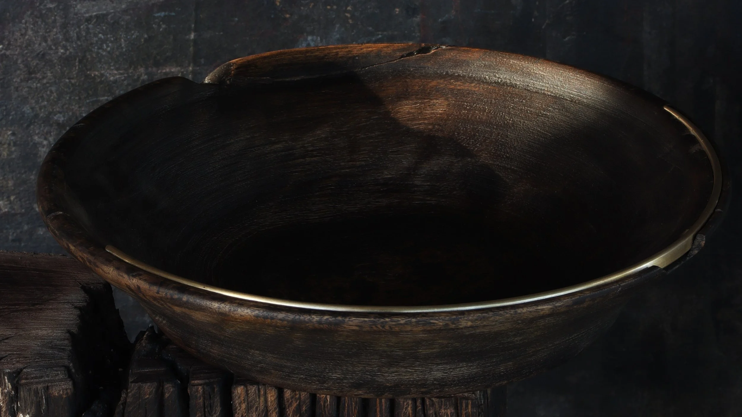 A wooden serving bowl with an elegant stainless steel strip inlayed on the edge