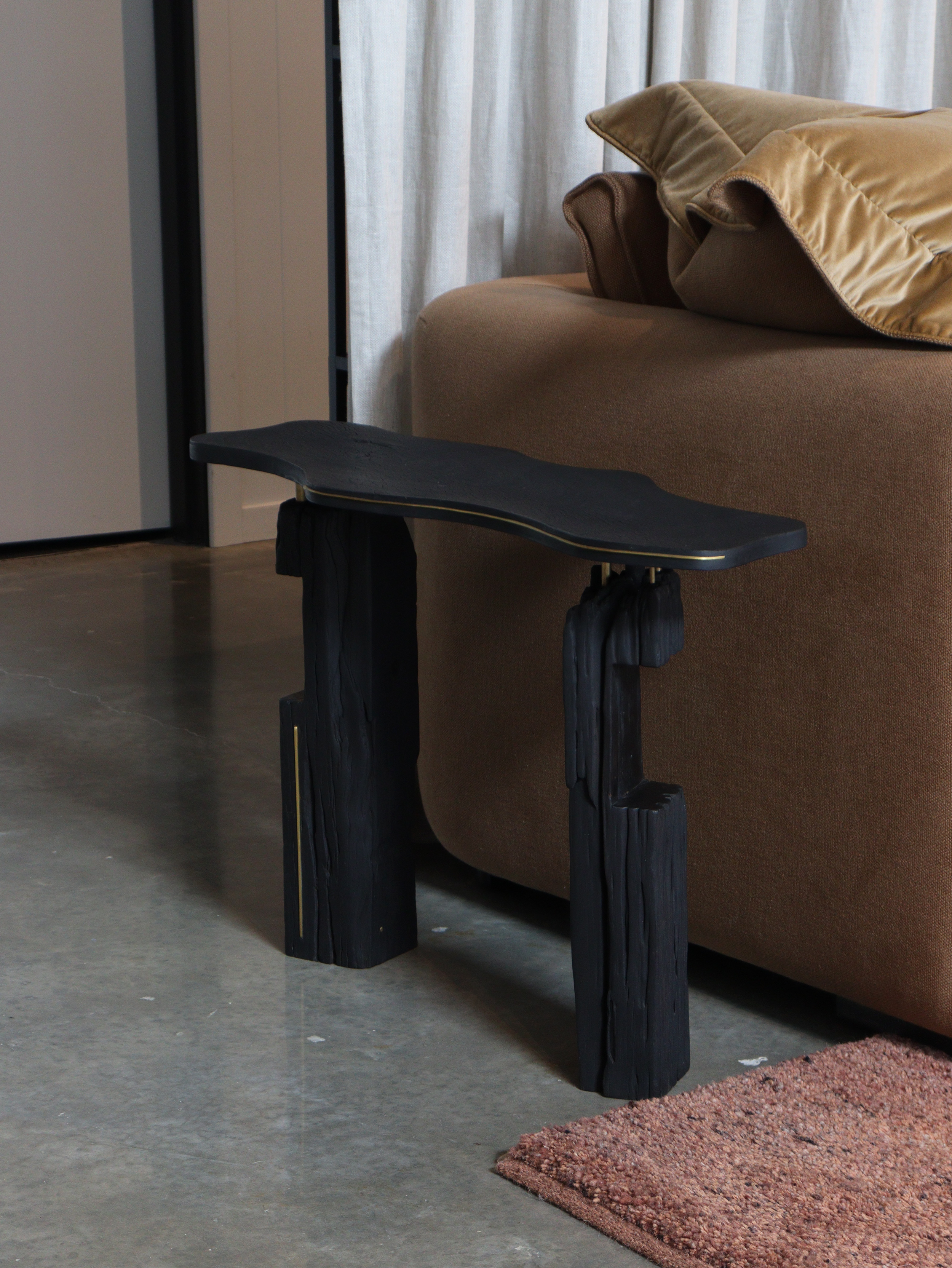 Black wooden sculptural side table in a designer showroom in byron bay