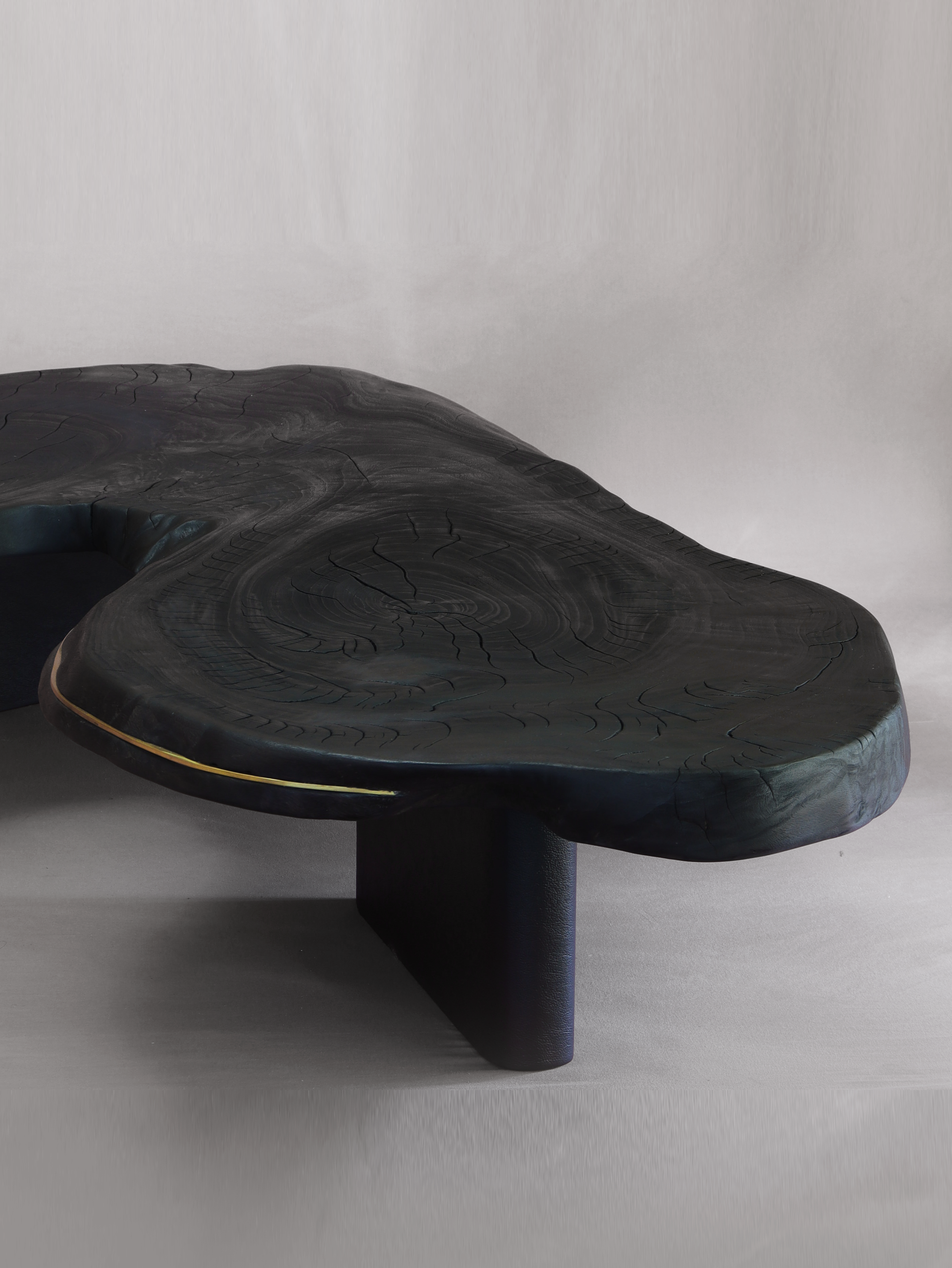 Close-up of a modern coffee table wooden finished with the art of shugi shi ban table with swirling grain of camphor laurel. curved, fluid shape.