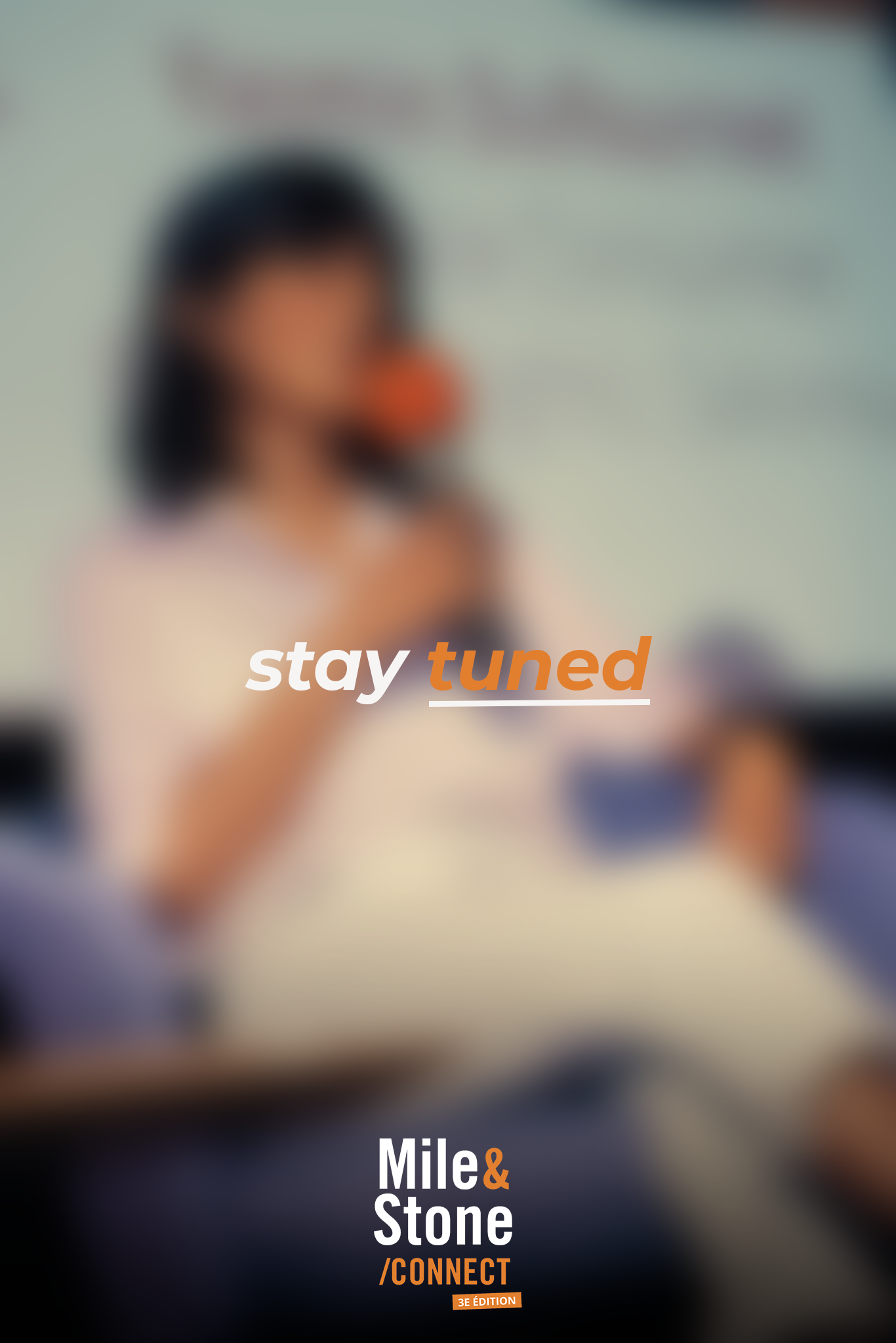 Une personne portant un t-shirt blanc, assise à un bureau, tenant une tasse, avec un fond flou et du texte en français et en anglais superposé