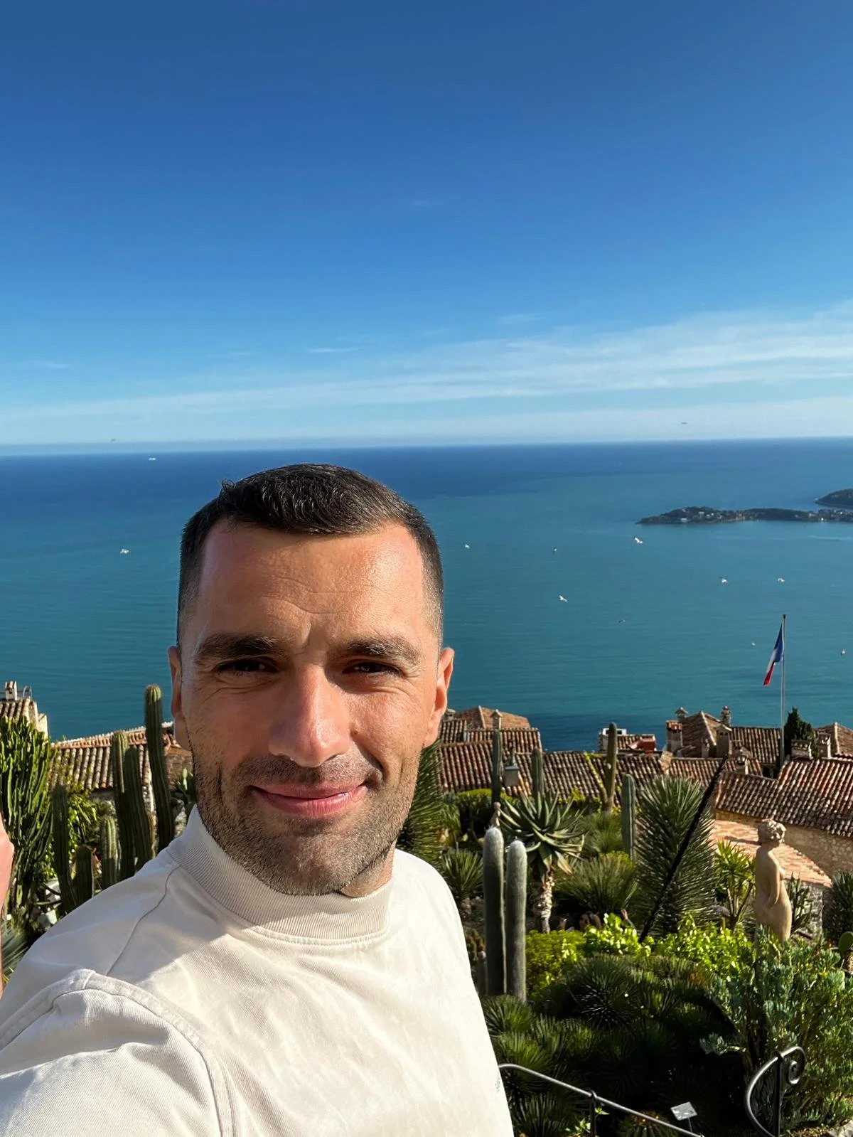 Ursu Iulian pe un vârf de deal, privind spre un oraș și marea în depărtare, simbol al libertății și al perspectivei câștigate prin trading.