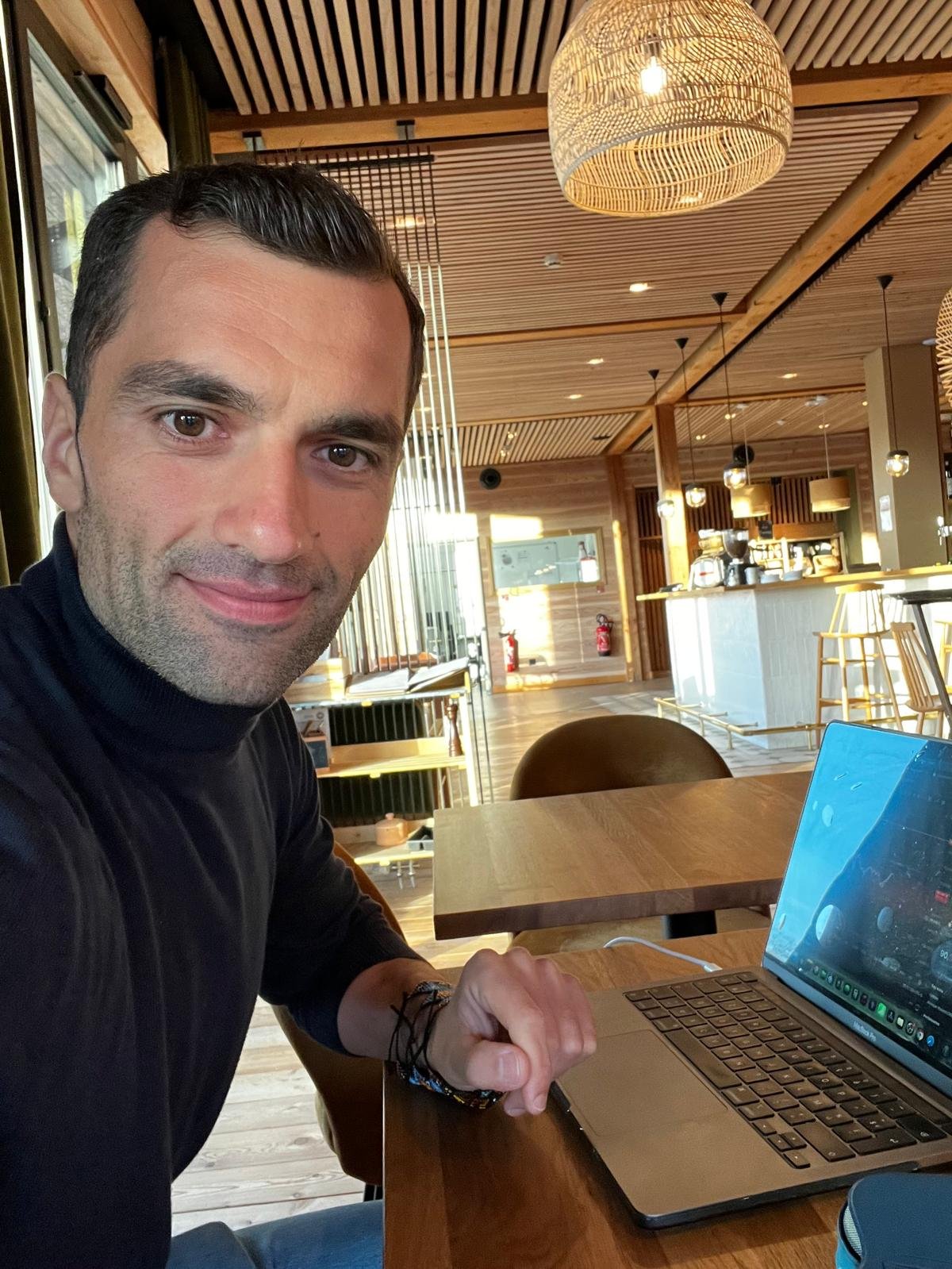 Ursu Iulian lucrând la laptop într-o cafenea, fondator Trade Grader.