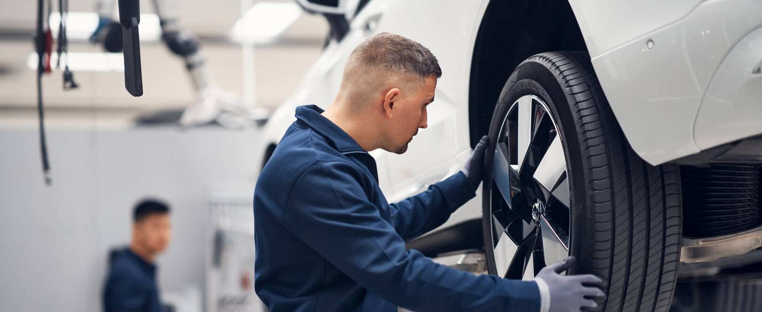 A Volvo Car certified technicians are changing a car tire in a garage.