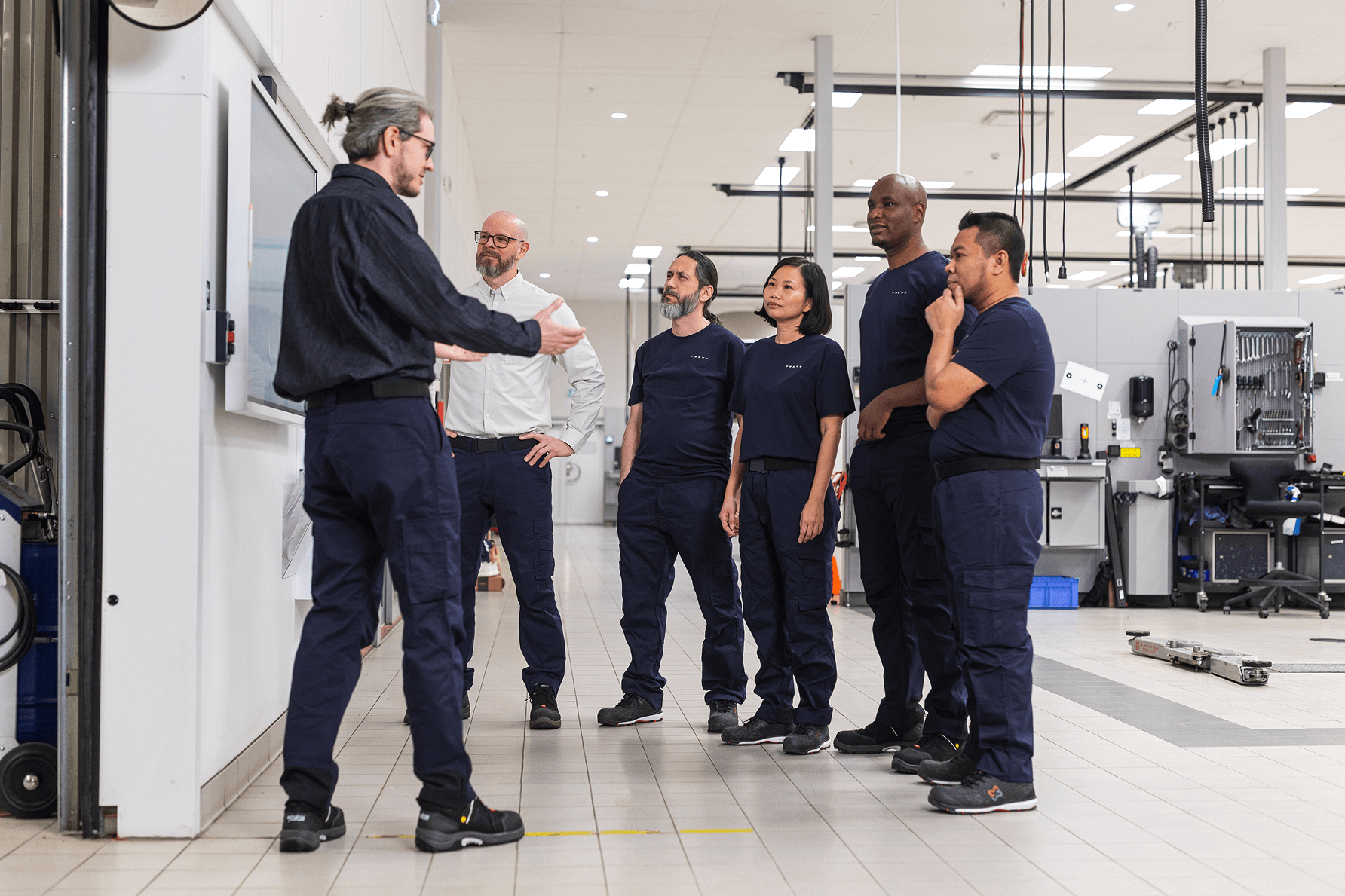The Volvo Apprenticeship Technician Program. A mentor describes something to a group of apprentice technicians in a Volvo workshop.