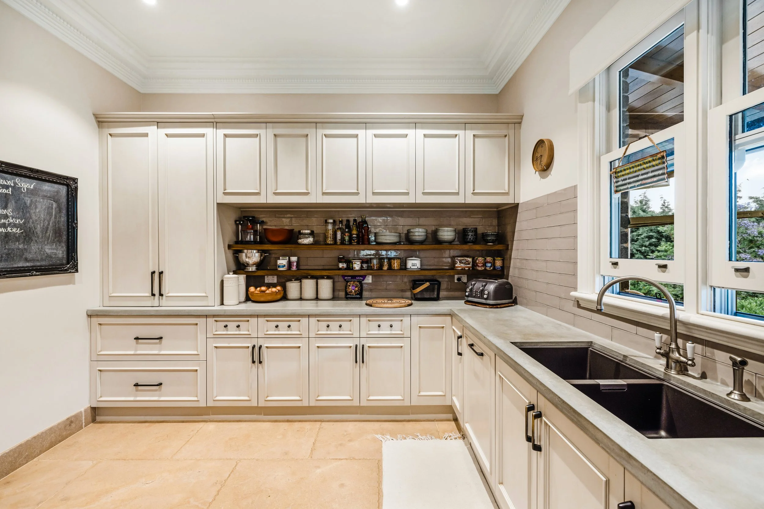 Butler Pantry, cream coloured cabinetry, concrete benchtop, timber shelves, Bronze undermount sink,  English tapware in Pewter colour, acid washed bronze cabinetry knobs and handles, timber double hung sash windows