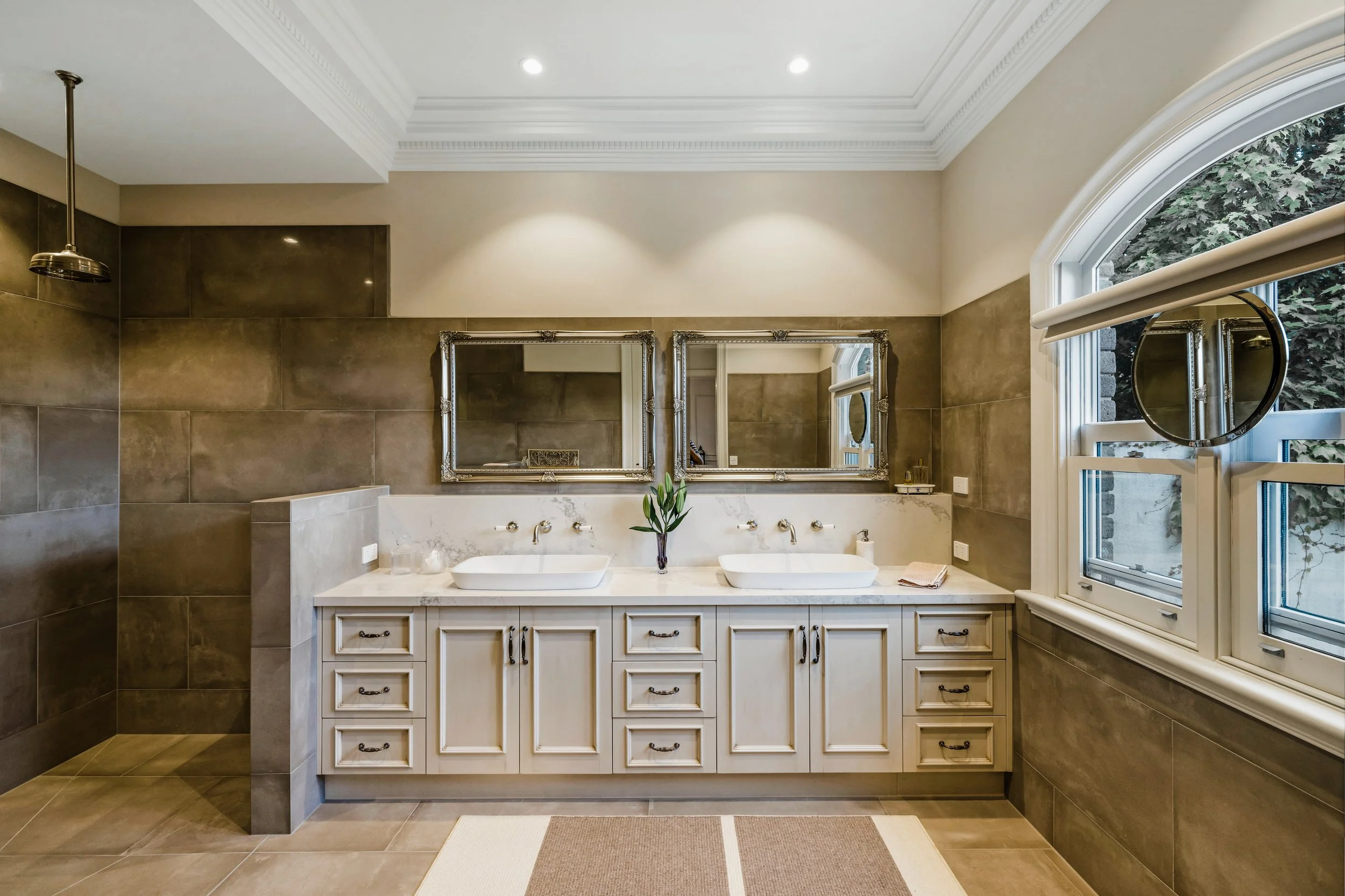 Luxury Ensuite Bathroom, grey porcelain tiles, wall mounted tapware, two white above counter basins, light coloured benchtop,  two rectangle decorative vanity mirrors, walk in shower