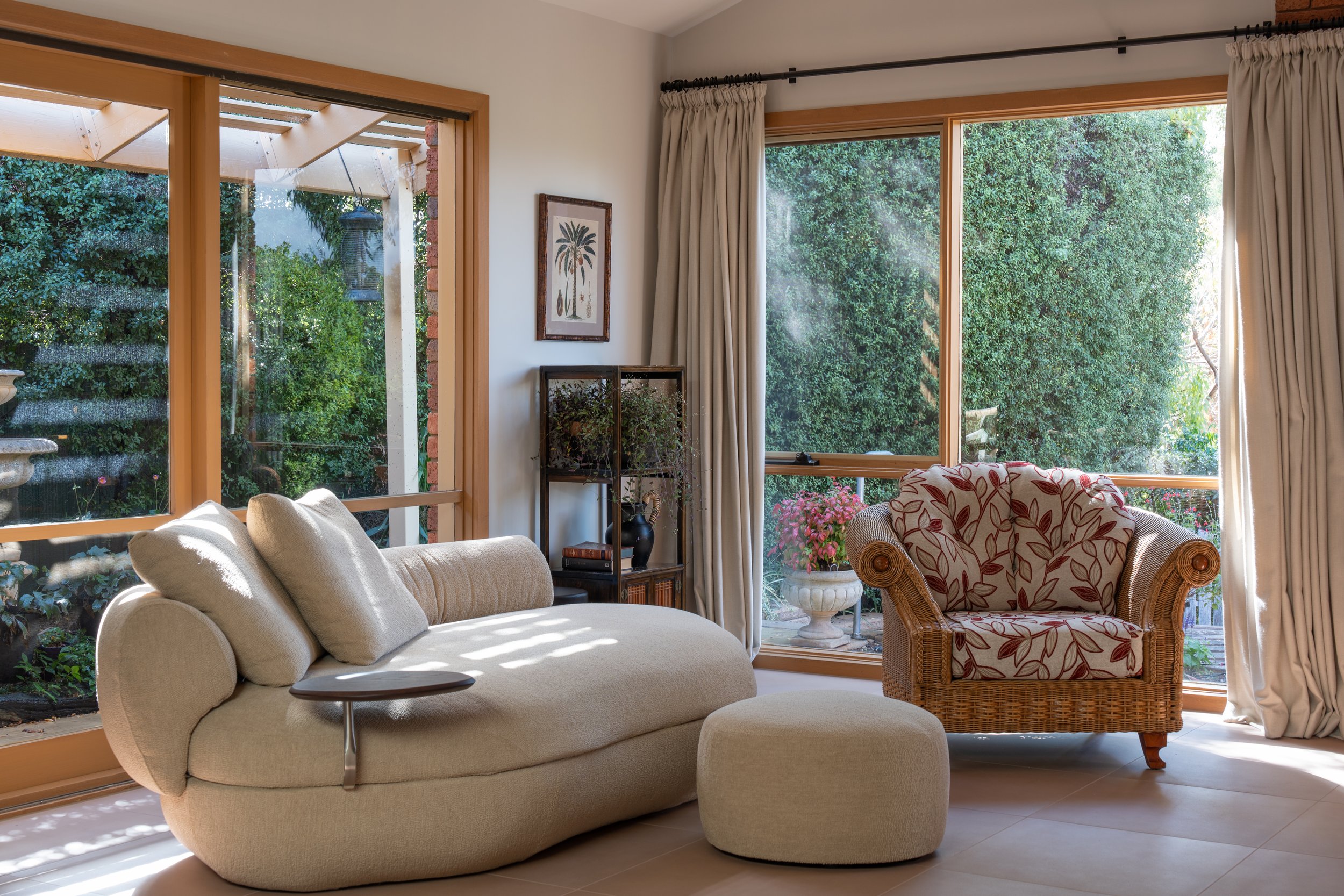 Light terracotta tiled floor, drapery on iron rod, rattan arm chair, modern organic form sofa