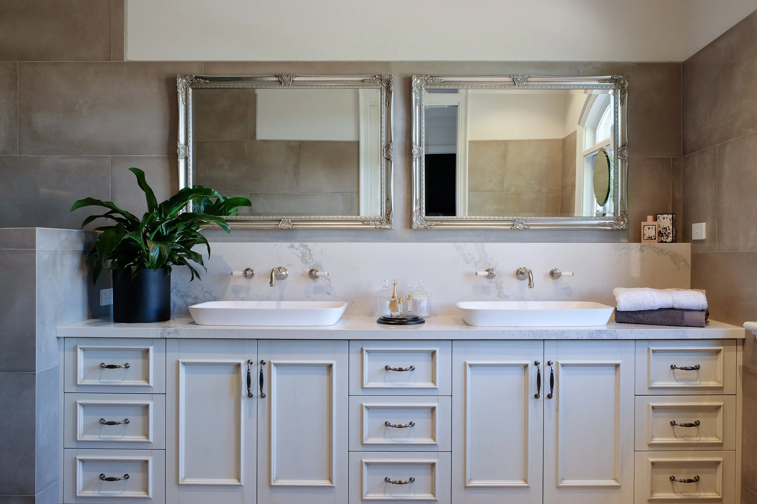 Luxury Ensuite Bathroom, grey porcelain wall tiles, wall mounted tapware, two white above counter basins, light coloured benchtop, traditional cabinetry with mouldings  two rectangle decorative vanity mirrors