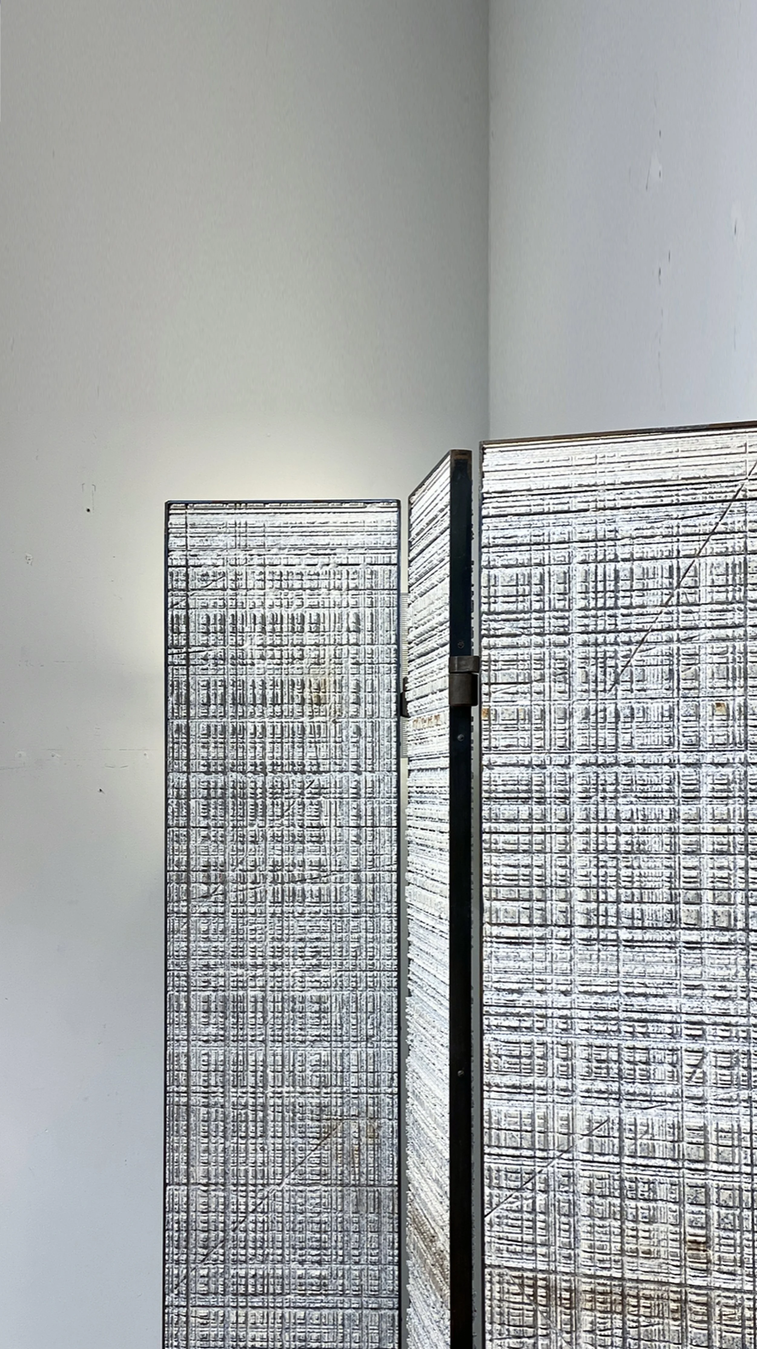 Benjamin Liatoud designs bespoke luxury architecture worldwide.Two metal privacy screens with textured patterns standing against a plain light-colored wall.