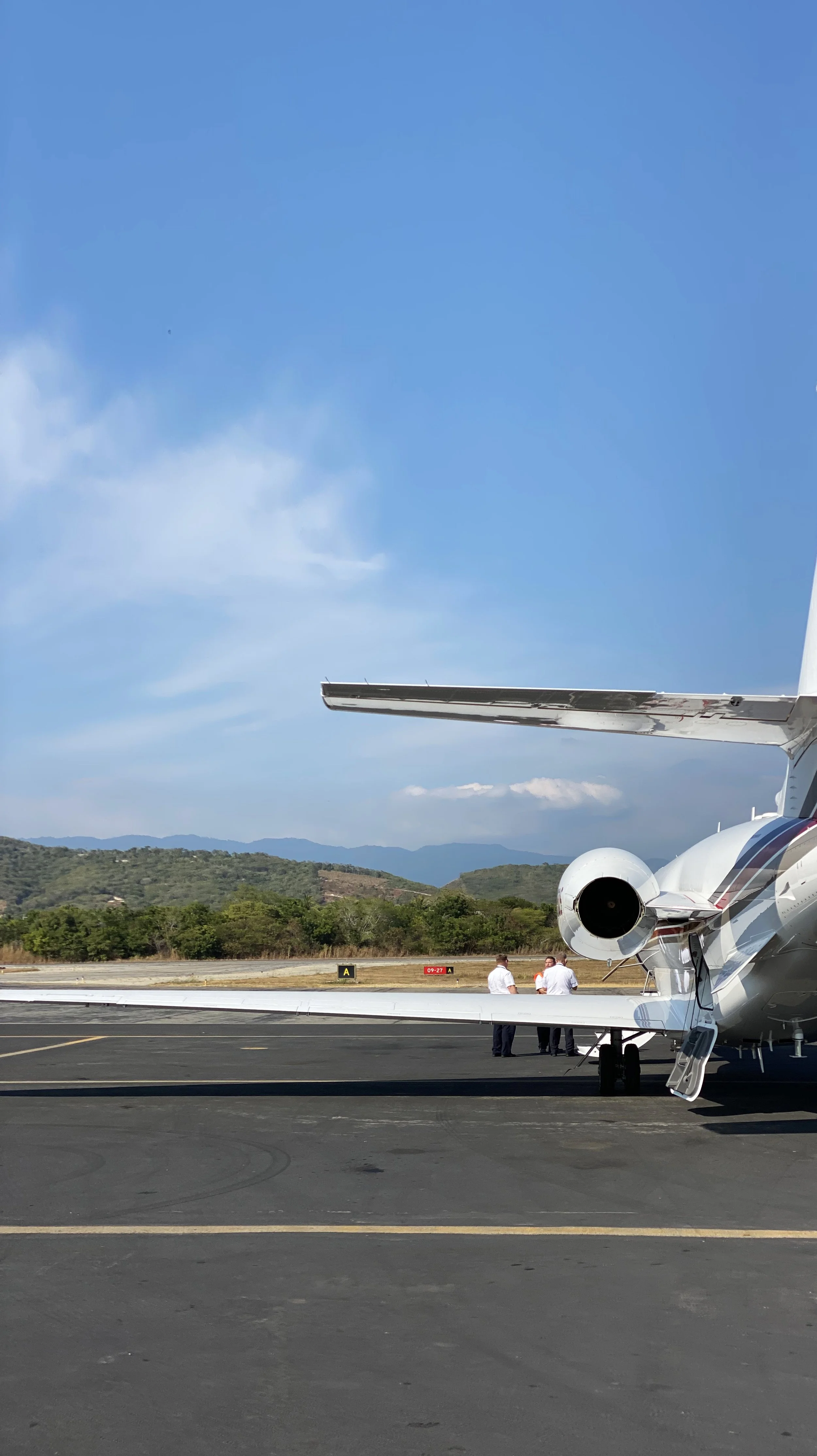 Private jet parked on the tarmac with a view of the mountains in the background and a clear blue sky.