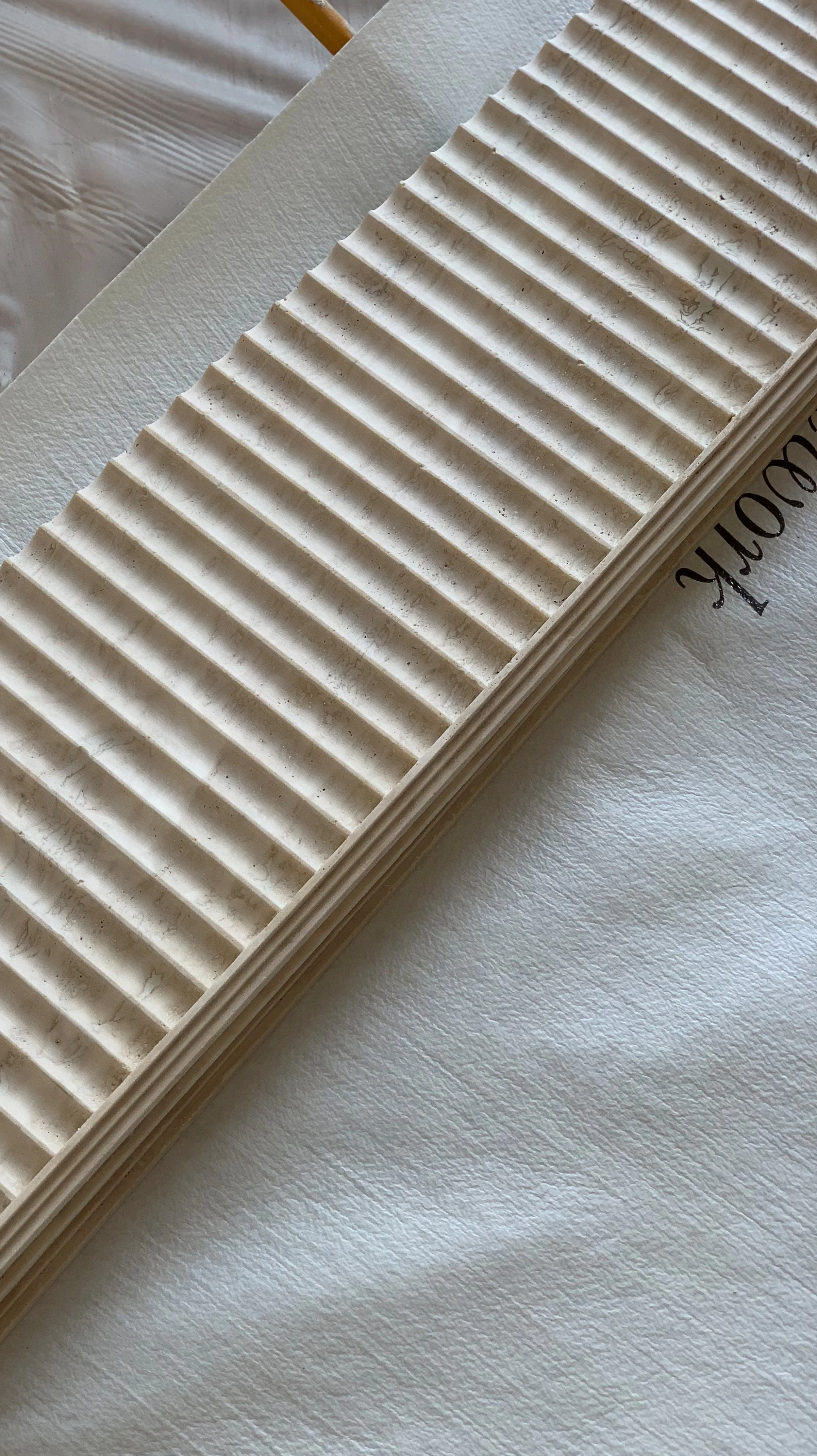 Close-up of a white, textured surface with a stack of beige corrugated paper sheets on top.