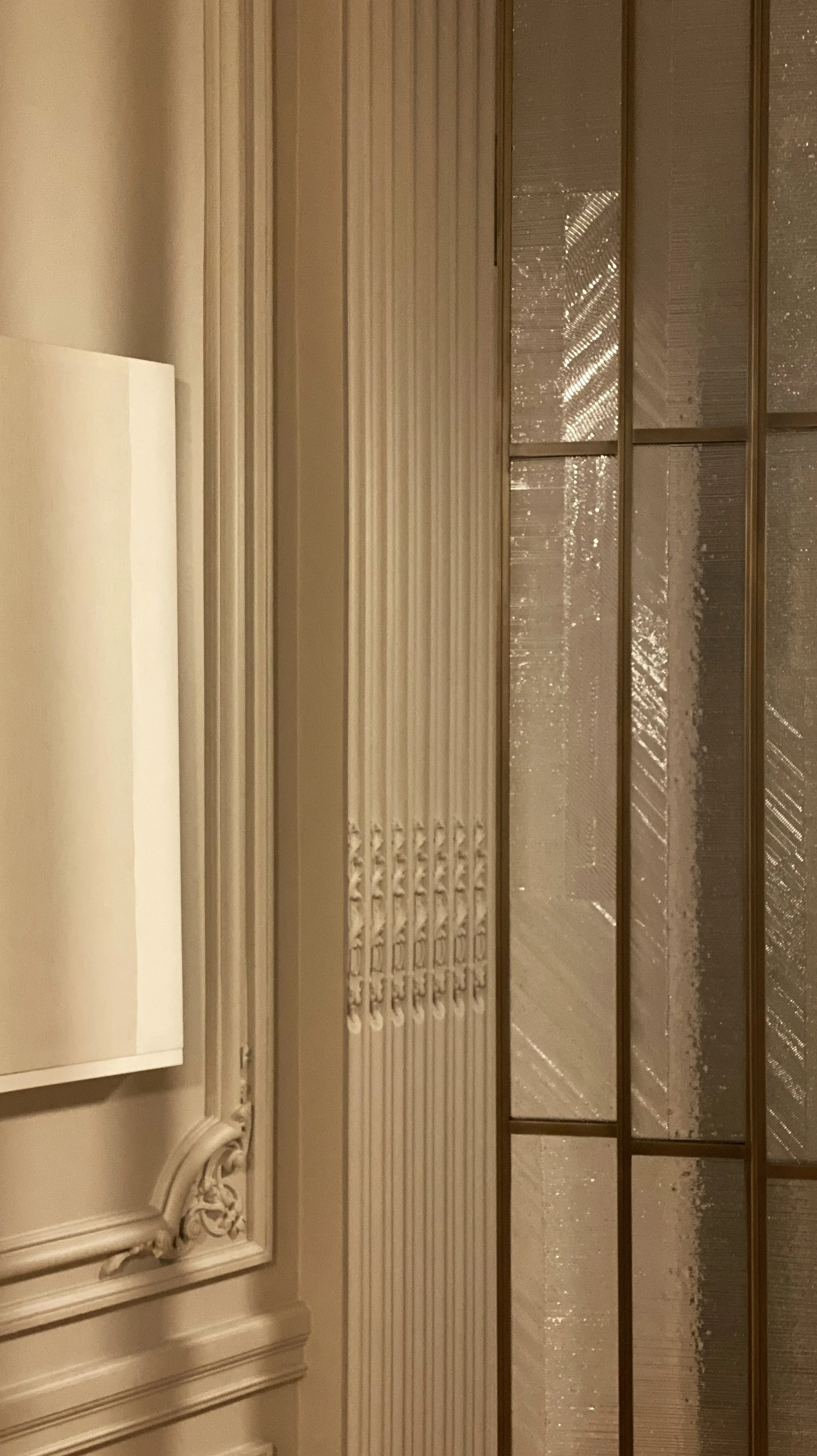Close-up of an ornate beige door with intricate moldings, a window with textured glass panels.